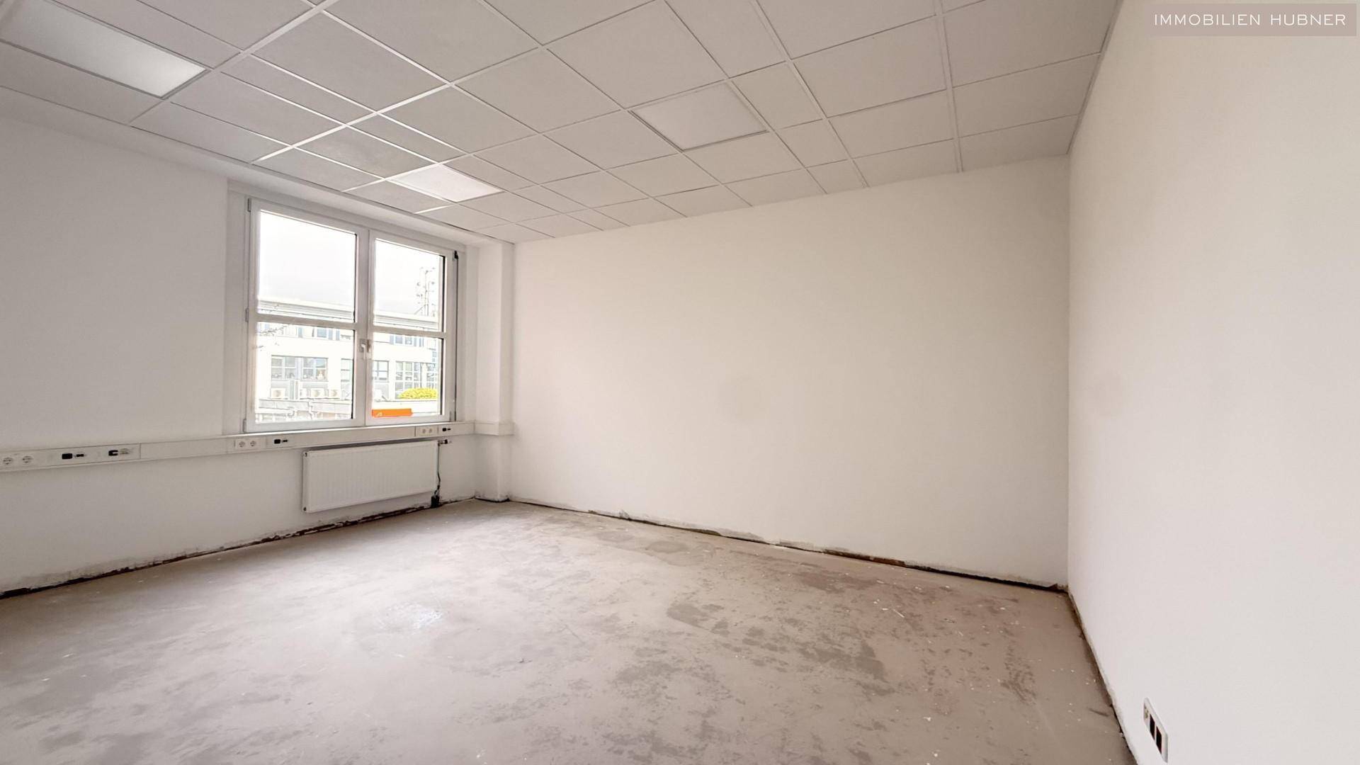 Kleineres, helles Büro mit einem großen Fenster und abgehängter Decke, ideal für Einzelarbeitsplätze.