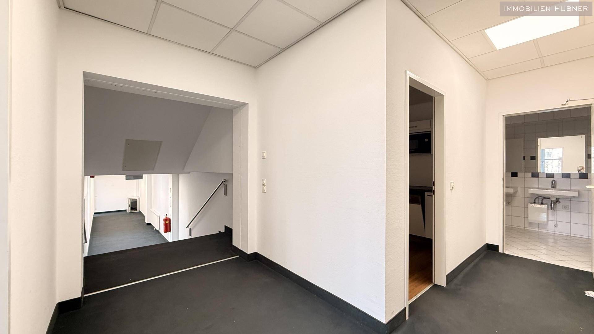 Flur mit Zugang zu Treppenhaus und weiteren Räumen, ausgestattet mit Teppichboden und Brandschutz.