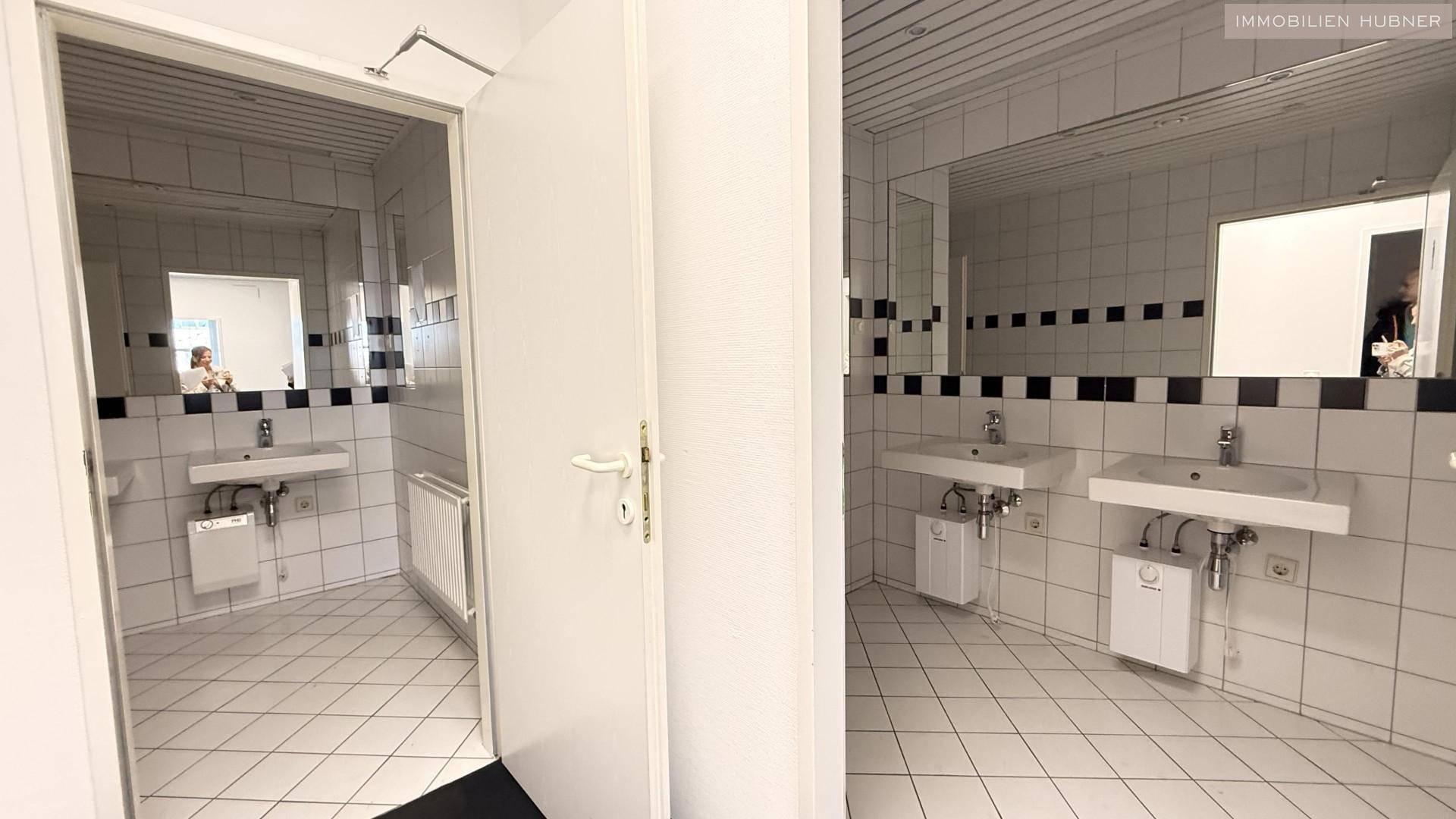 Badezimmer mit zwei Waschbecken, großen Spiegeln und weißen Fliesen, bietet ausreichend Platz.