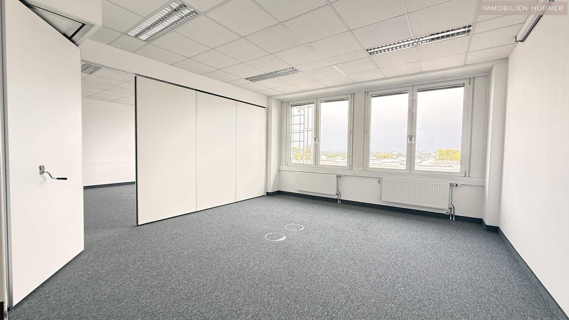 Flexibles Büro mit verschiebbaren Trennwänden und Teppichboden, ideal für variable Raumgestaltung.