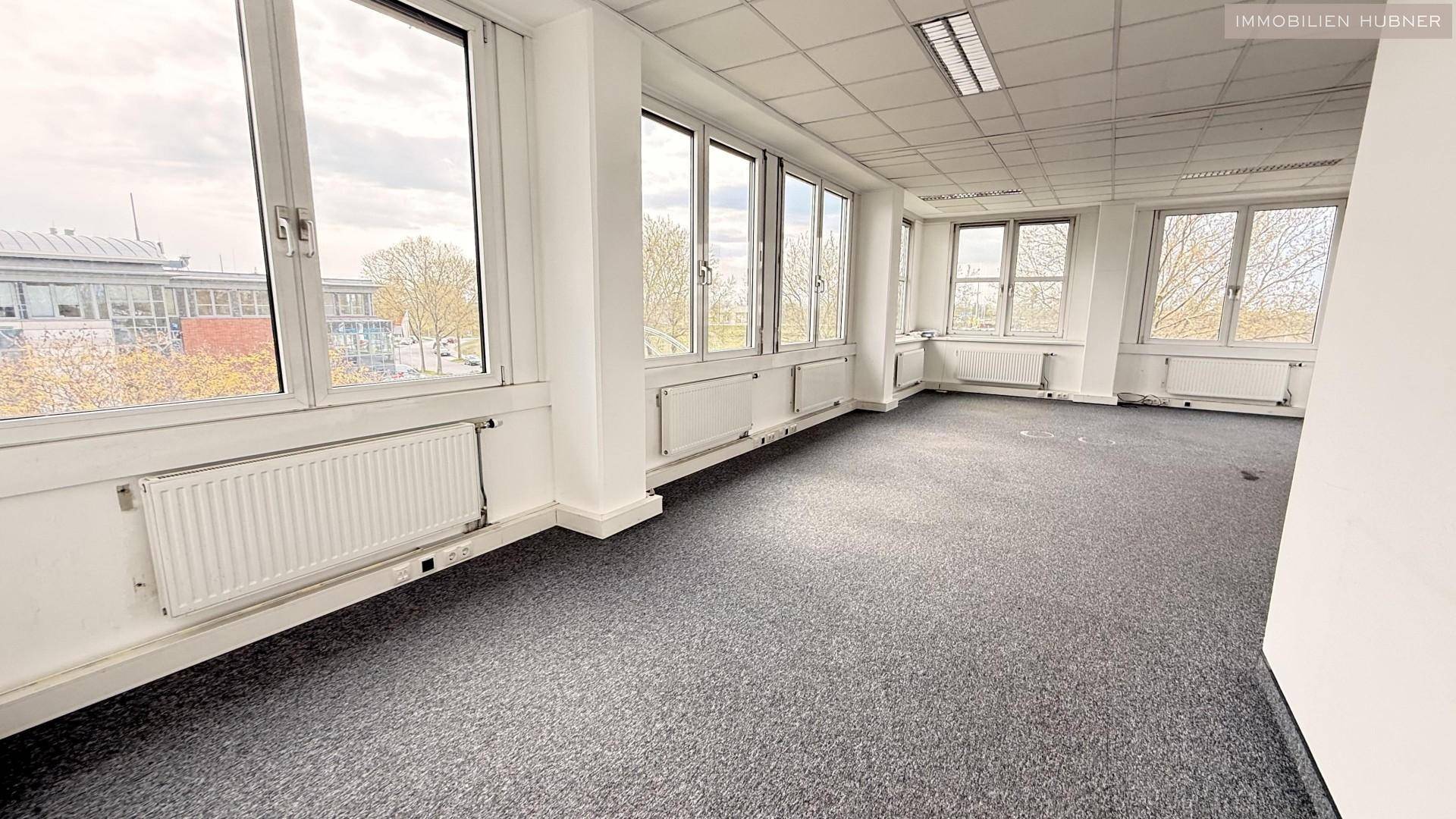 Weitläufiges Büro mit Teppichboden und durchgehender Fensterfront, bietet viel Tageslicht und Ausblick.