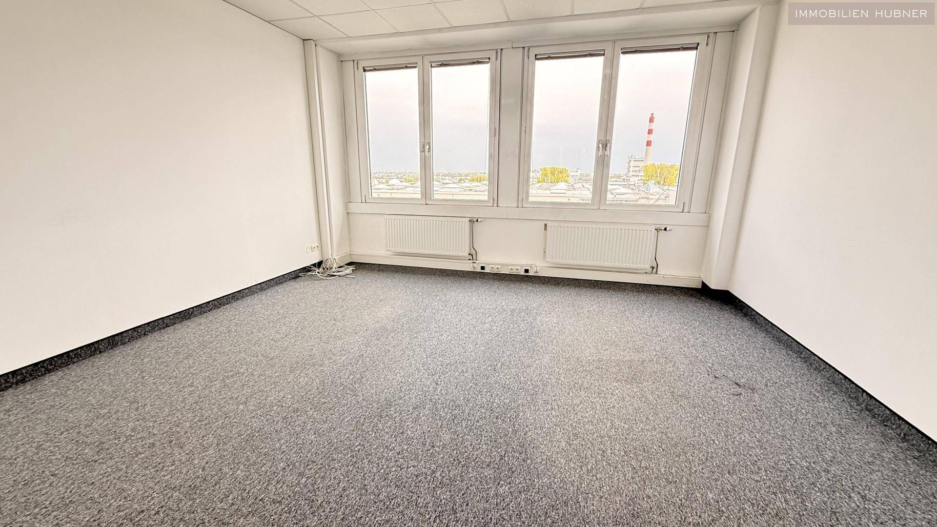 Kleineres Büro mit Teppichboden und Fensterfront, bietet eine ruhige Arbeitsatmosphäre.