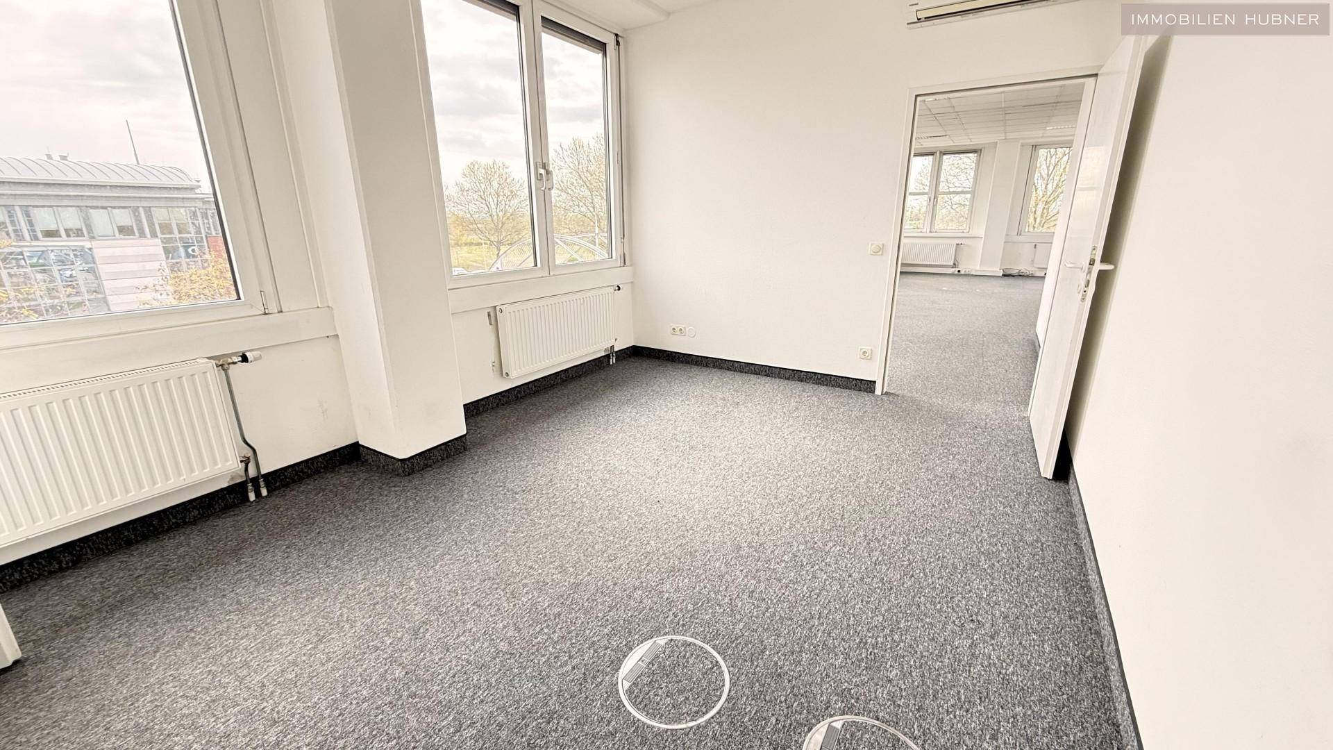 Eckbüro mit Teppichboden und Fenstern an zwei Seiten, bietet eine helle Arbeitsumgebung.
