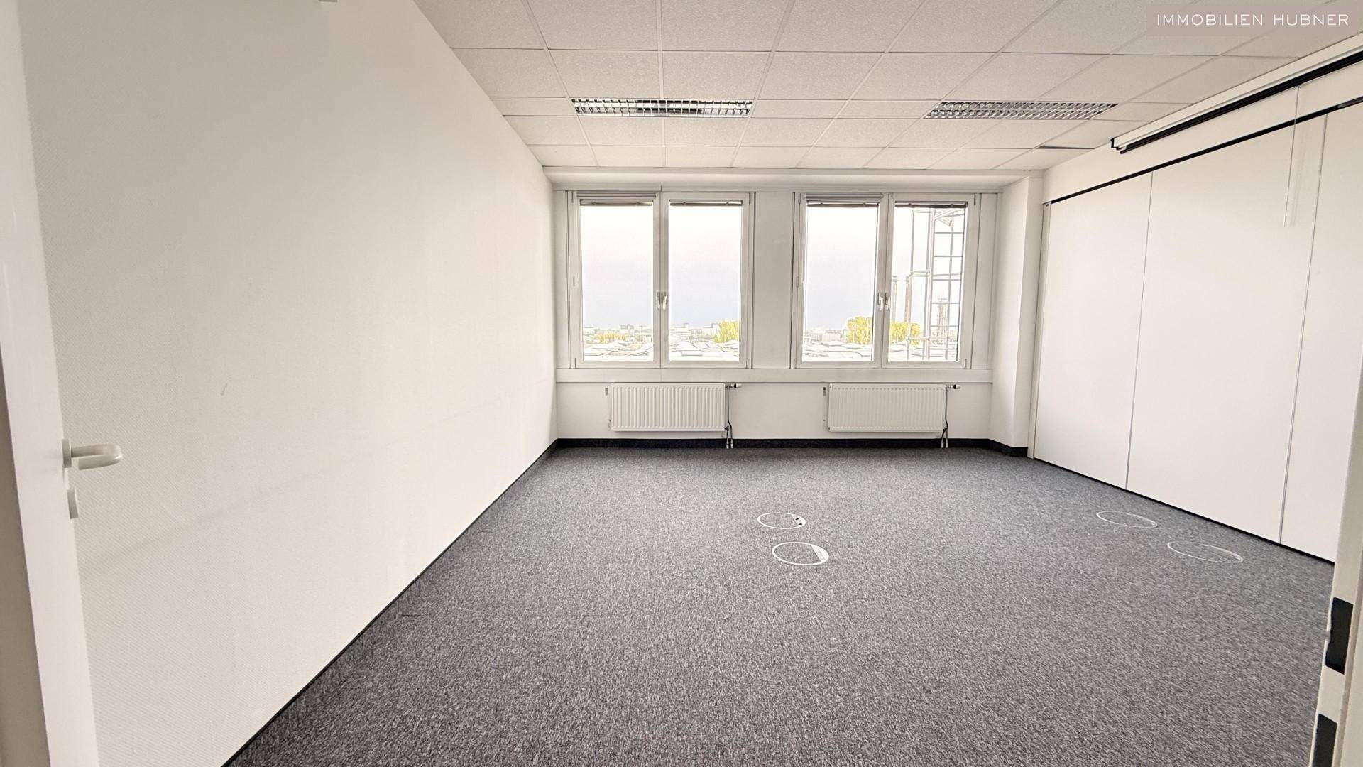 Büro mit Teppichboden und Fensterfront, bietet eine helle und funktionale Arbeitsumgebung.