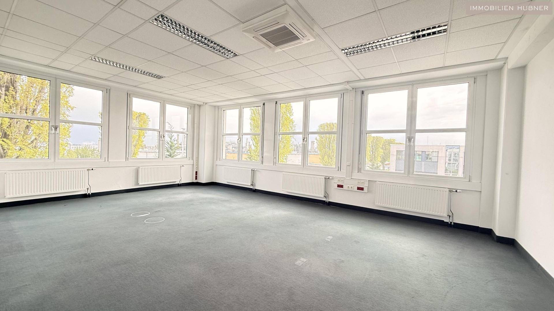 Großes, lichtdurchflutetes Büro mit Teppichboden und zahlreichen Fenstern, bietet eine weite Aussicht und flexible Nutzungsmöglichkeiten.