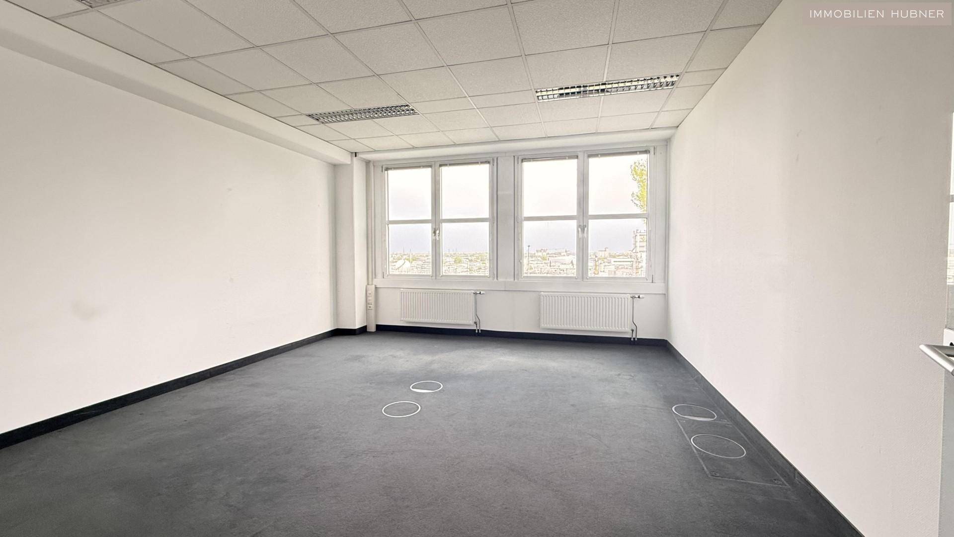 Geräumiges Büro mit Teppichboden und großen Fenstern, die viel Tageslicht hereinlassen und eine weite Aussicht bieten.