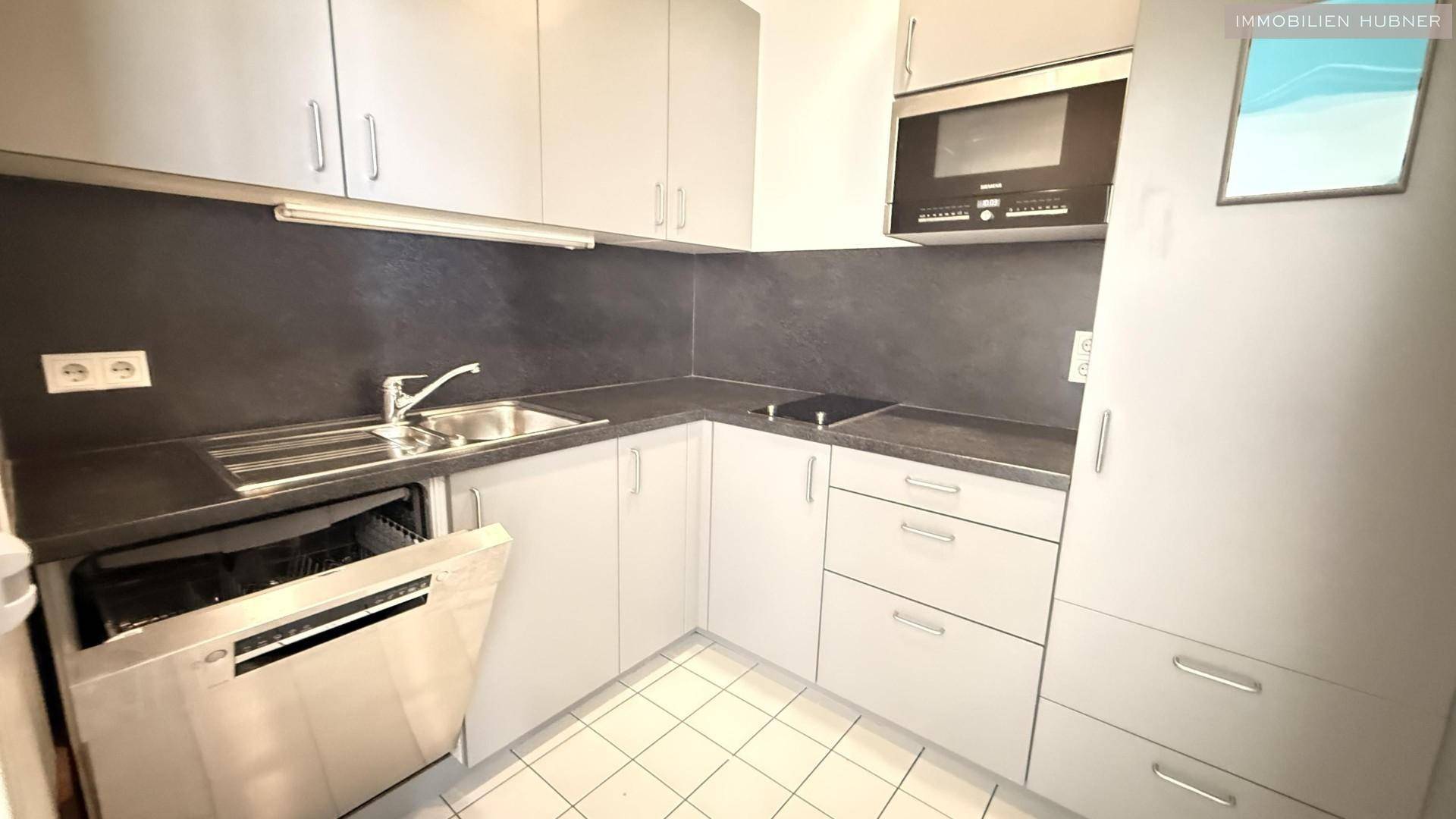 Moderne Küchenzeile in Grau mit integrierten Geräten und Fliesenboden, praktisch und funktional gestaltet.