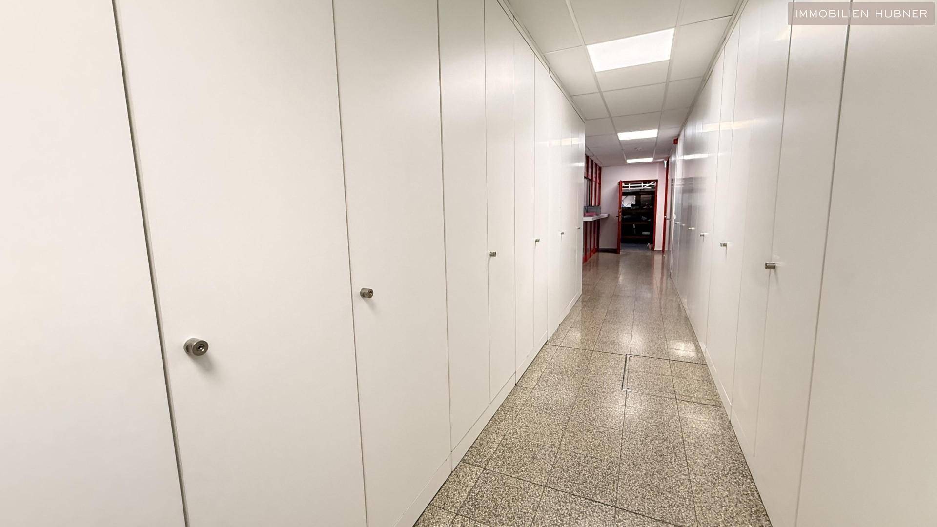 Langer Flur mit vielen weißen Einbauschränken und einem gefliesten Boden, der zu weiteren Räumen führt.