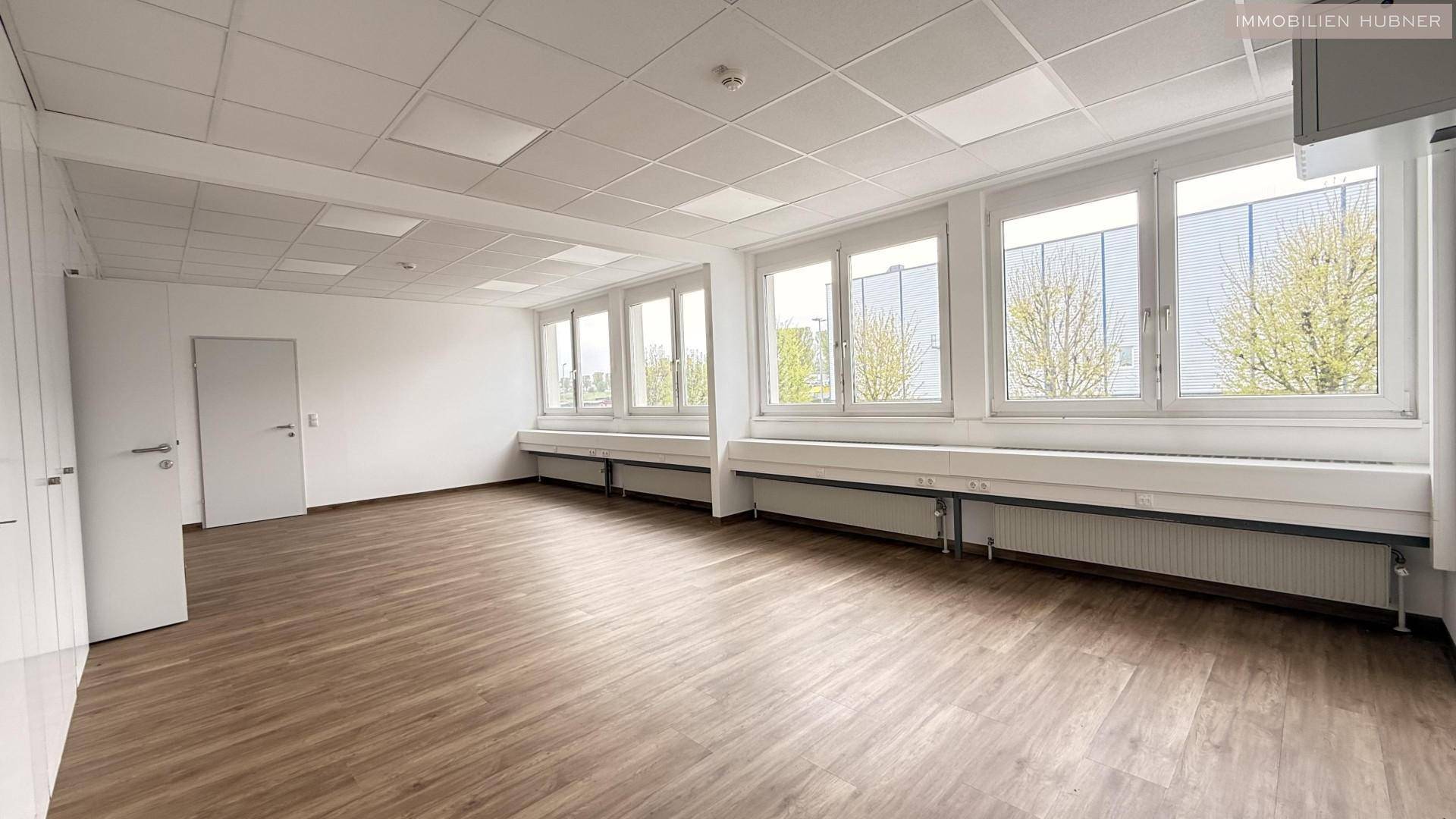 Geräumiger Büroraum mit vielen Fenstern, Laminatboden und weißer Decke, bereit zur individuellen Gestaltung.
