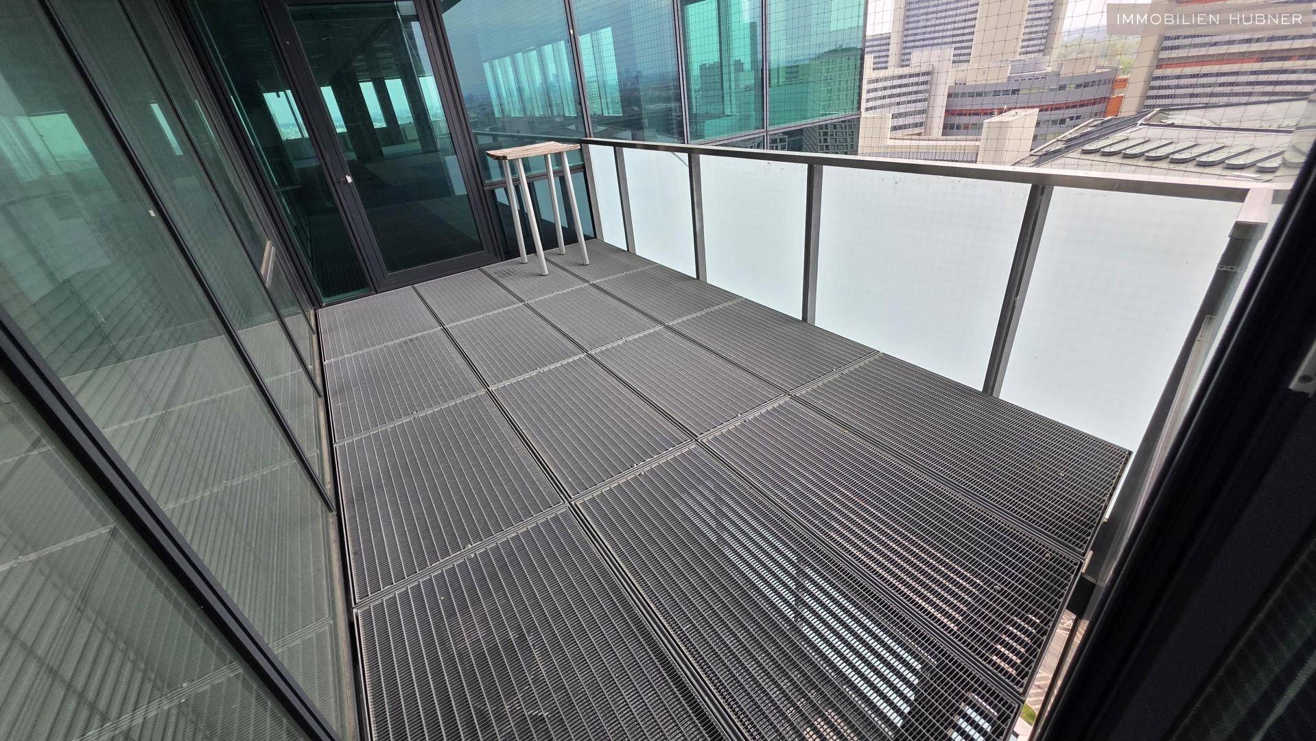 Kleiner Balkon mit Metallgitterboden und Glasbrüstung, ideal für eine kurze Pause.