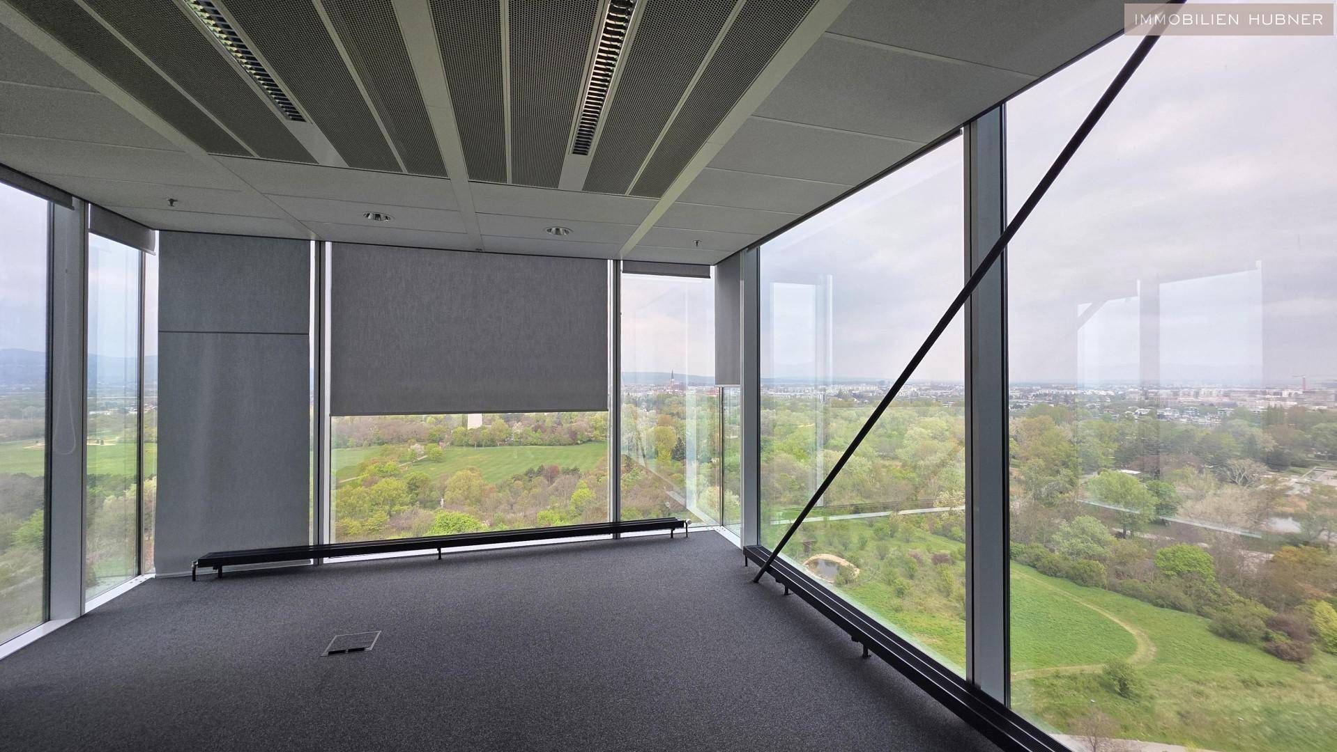 Helle Büroecke mit raumhohen Fenstern und weitem Blick auf die grüne Umgebung.