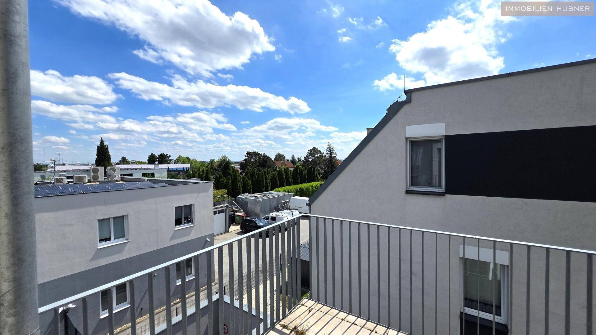Ausblick vom Balkon auf umliegende Gebäude und den weiten Himmel.