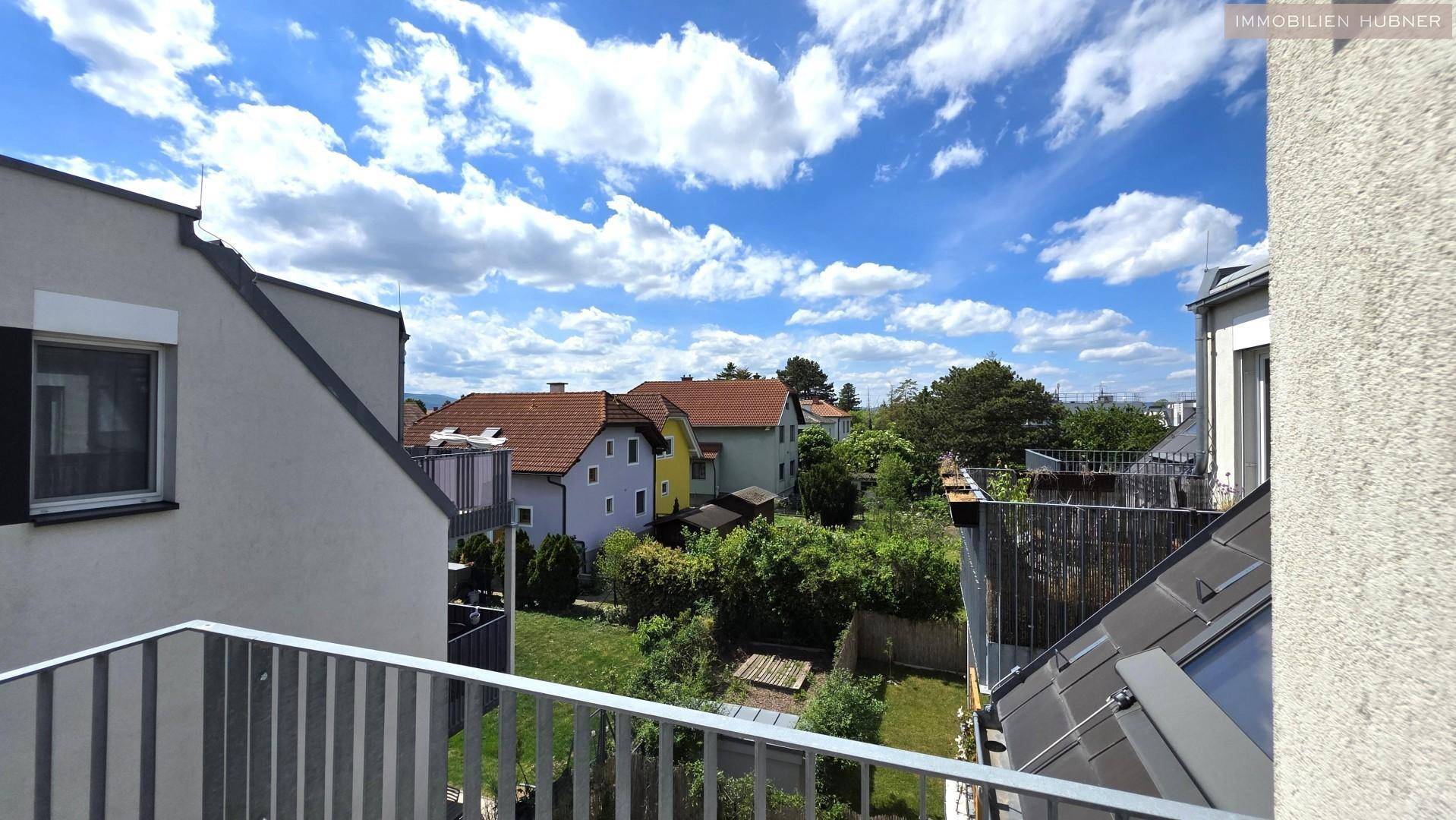 Panoramablick vom Balkon auf benachbarte Häuser und grüne Gärten.
