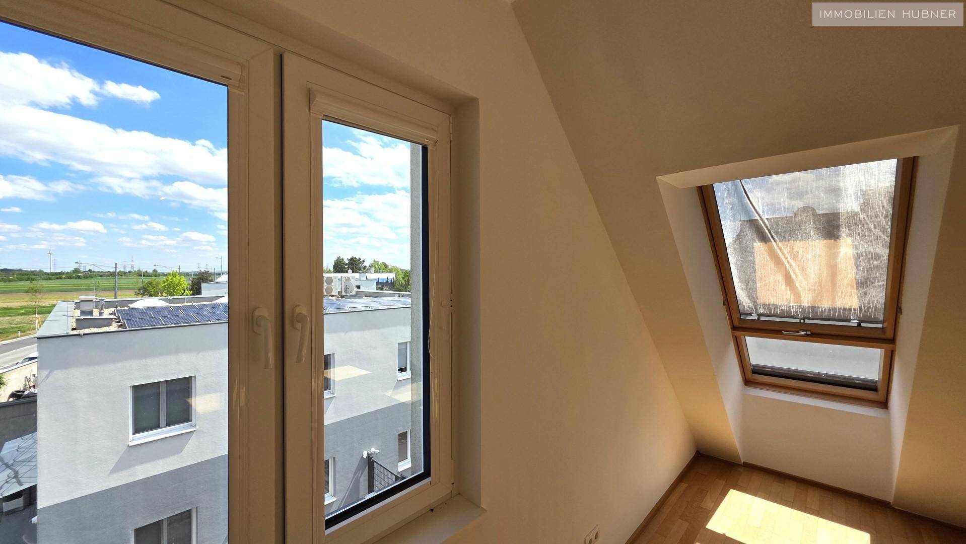 Fenster mit Blick auf ein Nachbargebäude und Dachfenster, das zusätzlichen Lichteinfall bietet.