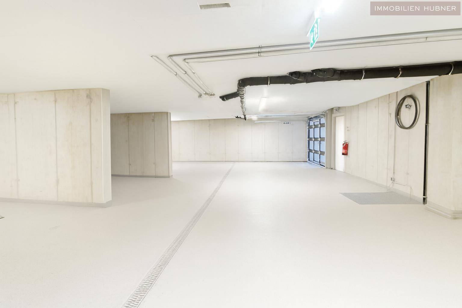 Weitläufige Tiefgarage mit glattem Boden und Zugang zum Gebäude, bietet Komfort und Sicherheit.