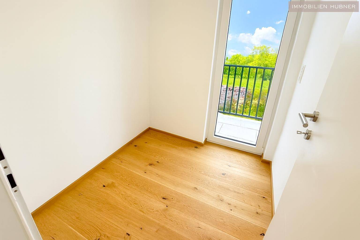 Kleiner, heller Raum mit Holzboden und Zugang zu einem französischen Balkon, ideal als Arbeitszimmer.