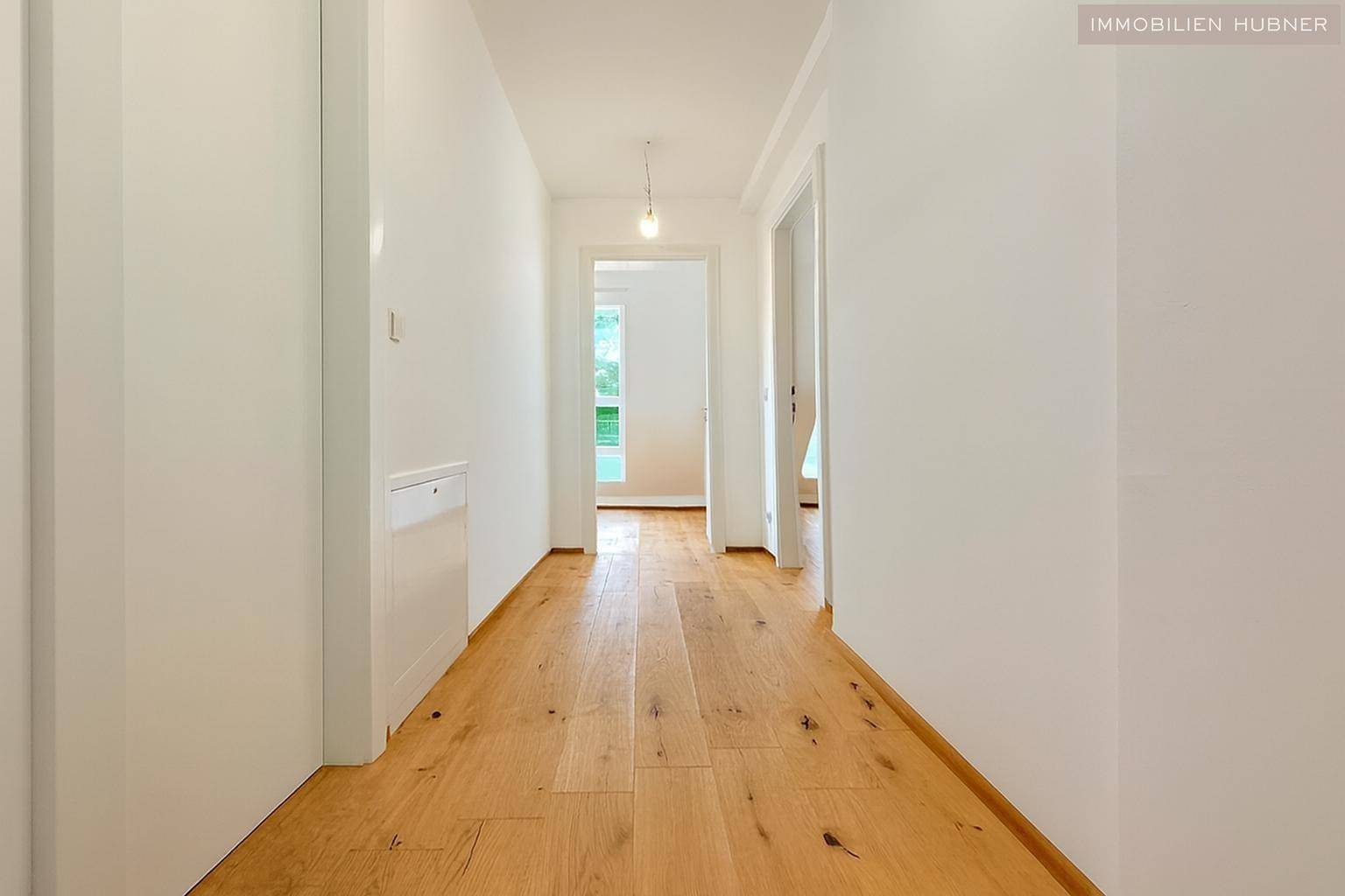 Heller Flur mit Holzboden und Zugang zu verschiedenen Räumen der Wohnung, sehr einladend.