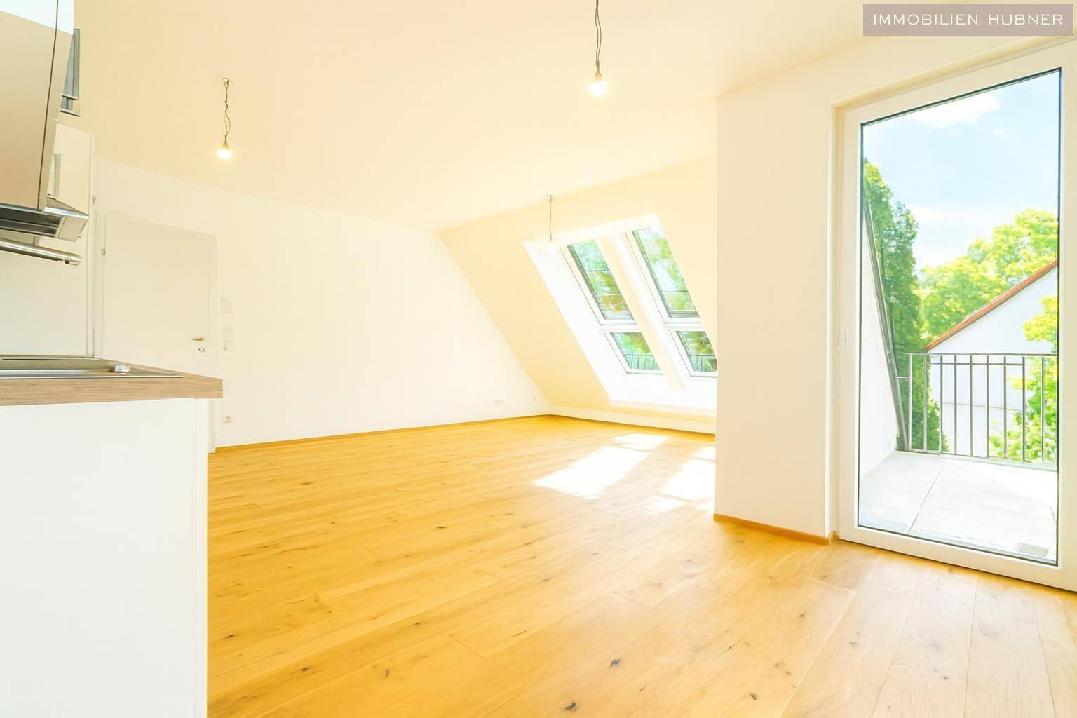 Lichtdurchfluteter Wohnbereich mit Holzboden, Dachfenstern und Zugang zur Terrasse, sehr einladend.
