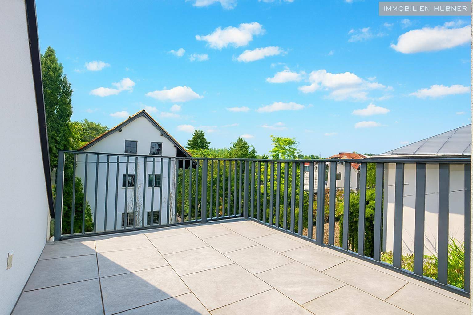 Geräumige Dachterrasse mit Fliesenboden und Blick auf die umliegende Wohngegend, perfekt zum Entspannen.
