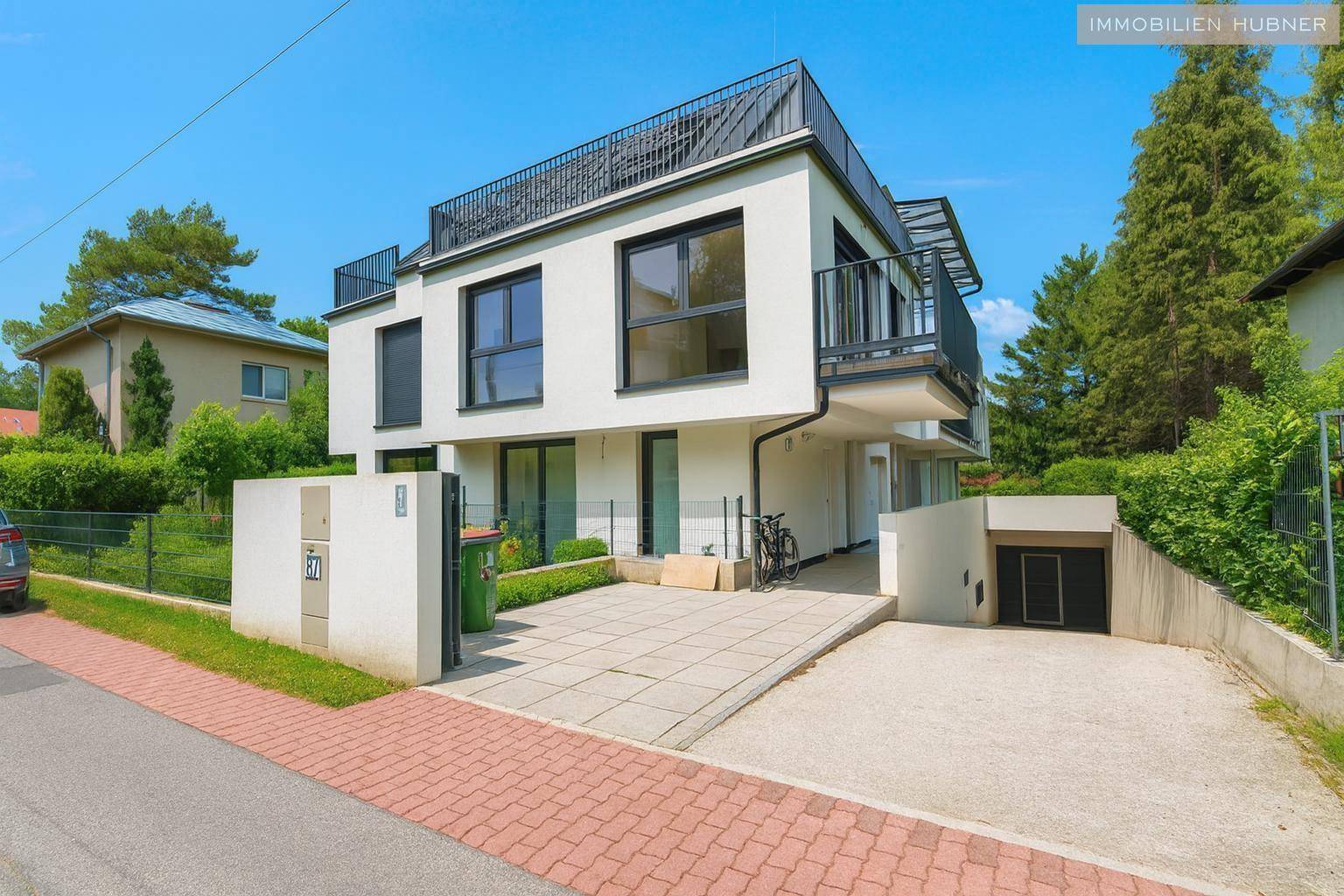 Modernes Mehrfamilienhaus mit Balkonen, Tiefgaragenzufahrt und gepflegter Außenanlage.