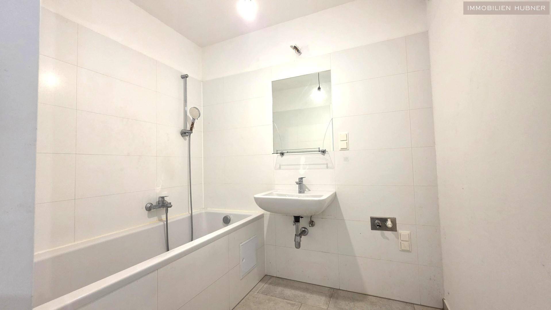 Modernes Badezimmer mit Badewanne, Waschbecken und weißen Fliesen.