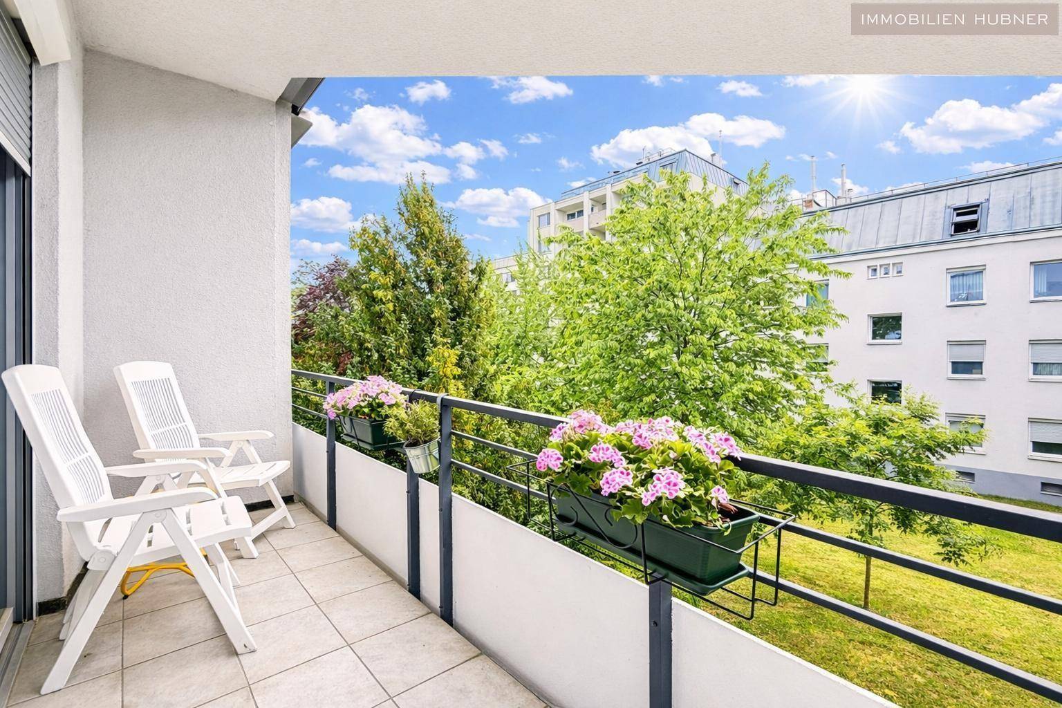Sonniger Balkon mit Fliesenboden und Gartenmöbeln, ideal zum Entspannen im Freien.