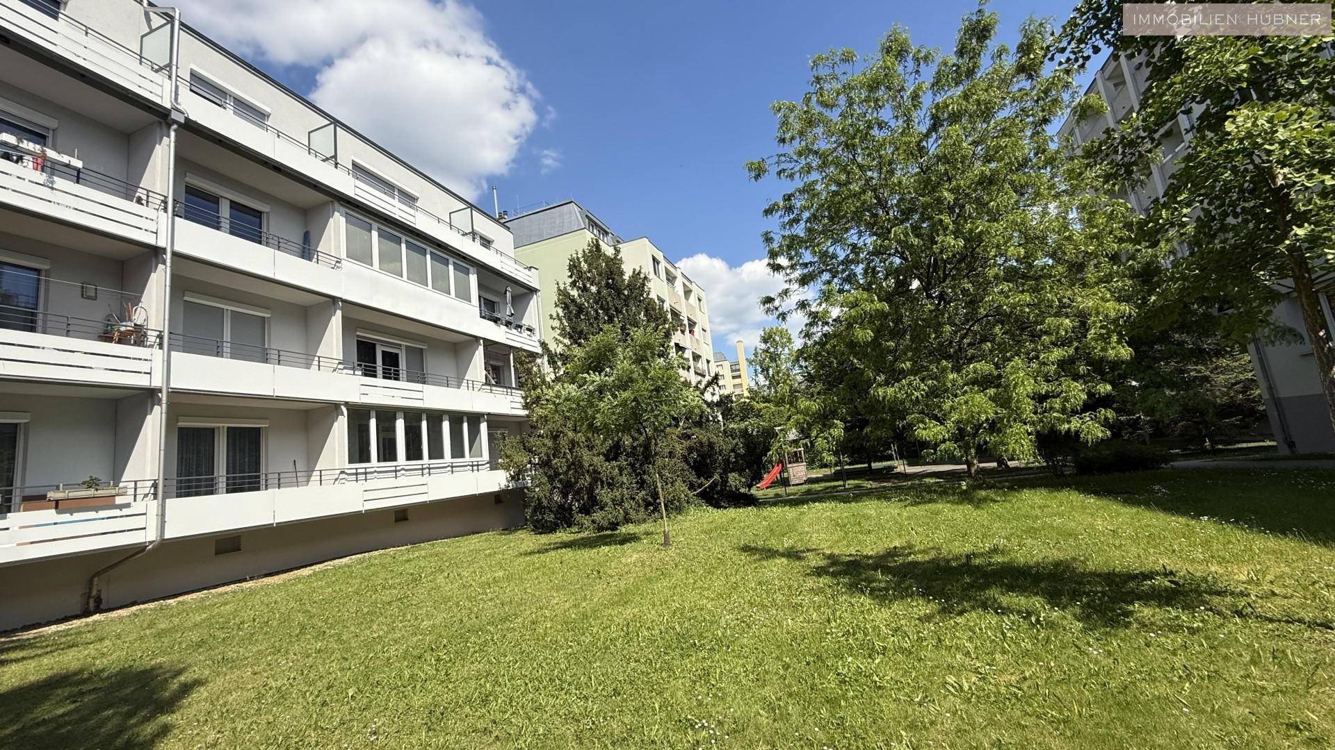 Grüne Außenanlage mit Rasenflächen und Bäumen, ideal für Erholung und Spiel.