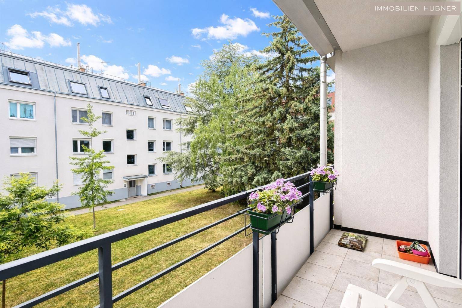Geräumiger Balkon mit Blick auf die grüne Wohnanlage und hohe Bäume, bietet viel Ruhe.