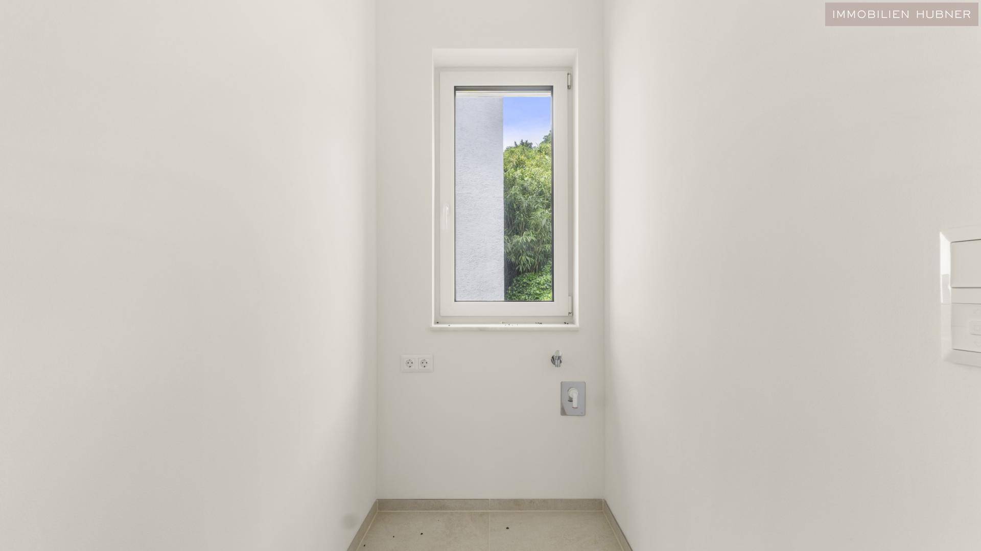 Kleiner Hauswirtschaftsraum mit Fenster, Anschlüssen für Waschmaschine und Trockner.