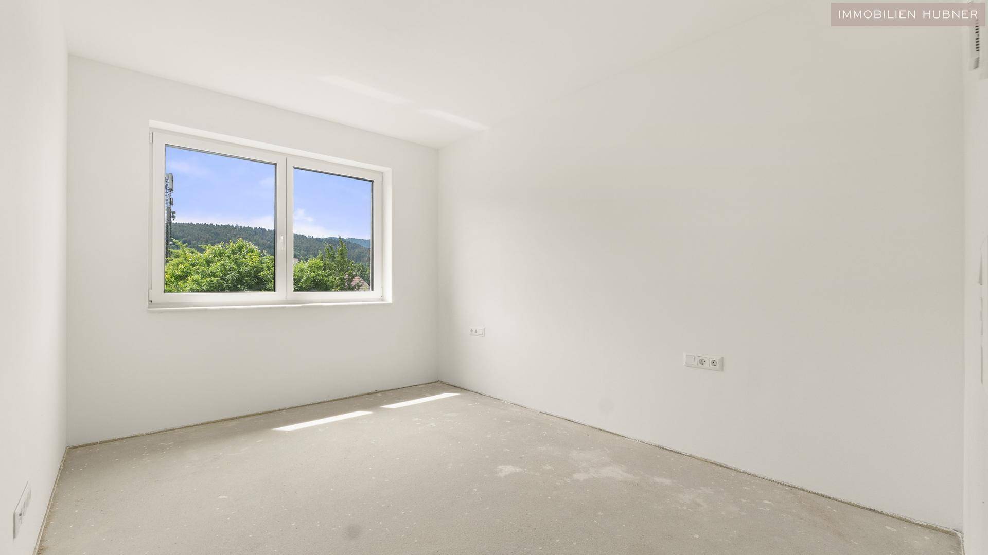 Helles, unmöbliertes Zimmer mit großem Fenster und Blick auf die umliegende Hügellandschaft.