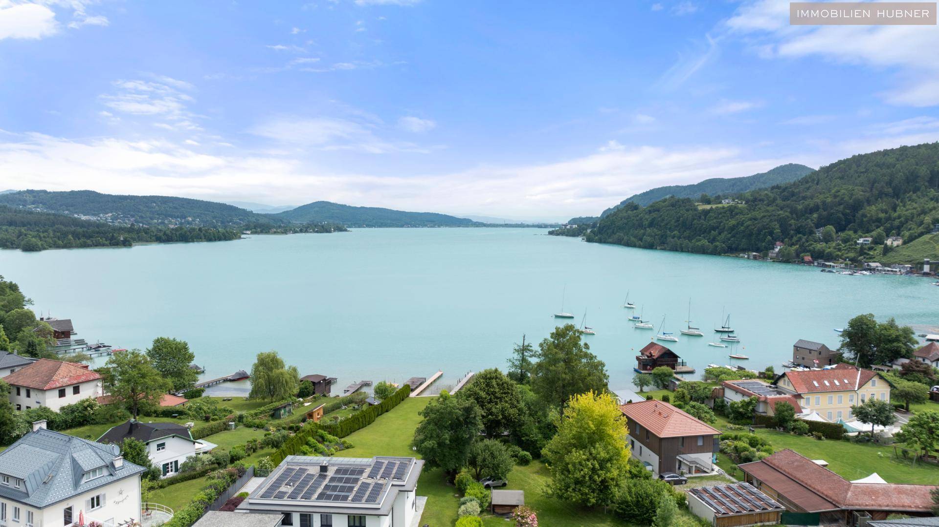 Atemberaubender Panoramablick auf einen großen See, umgeben von grünen Hügeln und Häusern.