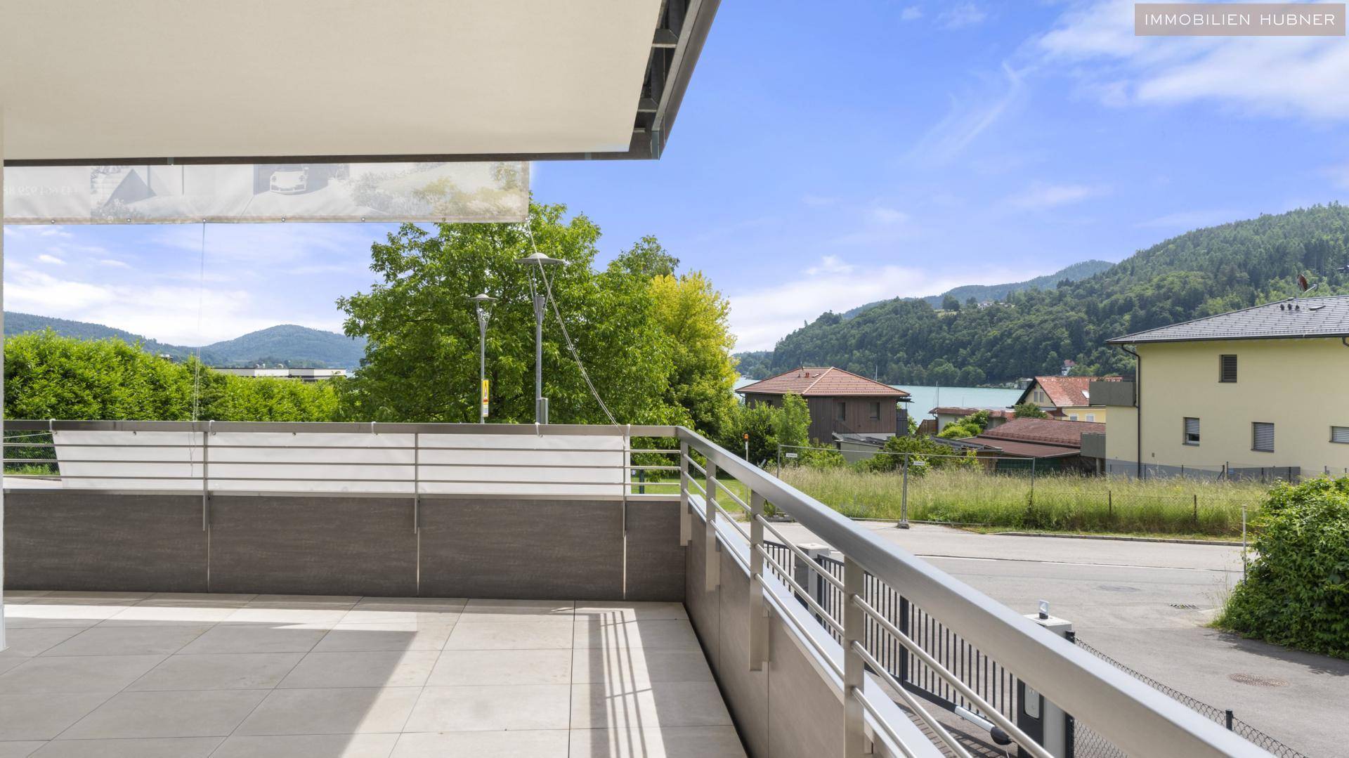 Geräumiger Balkon mit Fliesenboden und weitem Blick auf den See und die umliegenden Berge.