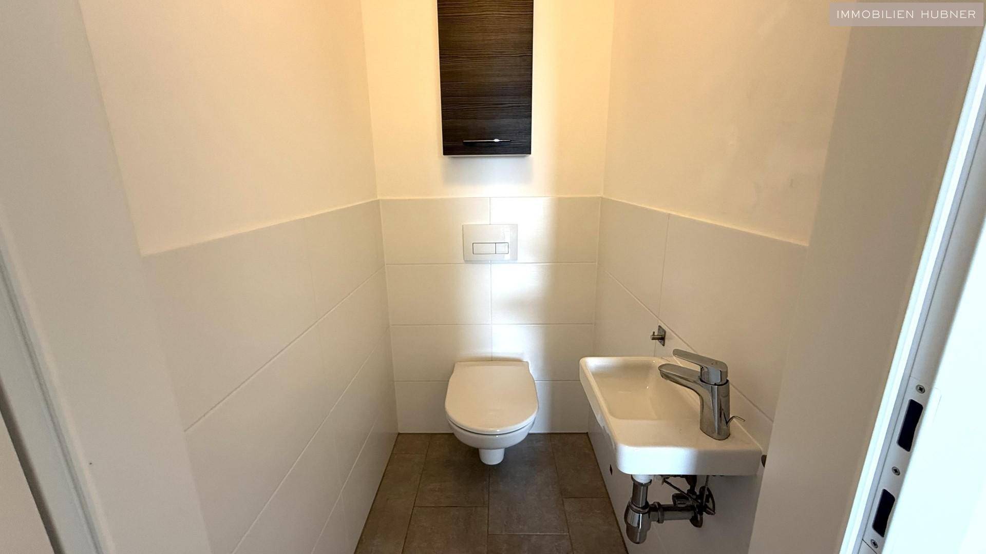 Separates Gäste-WC mit wandhängendem WC und kleinem Handwaschbecken.