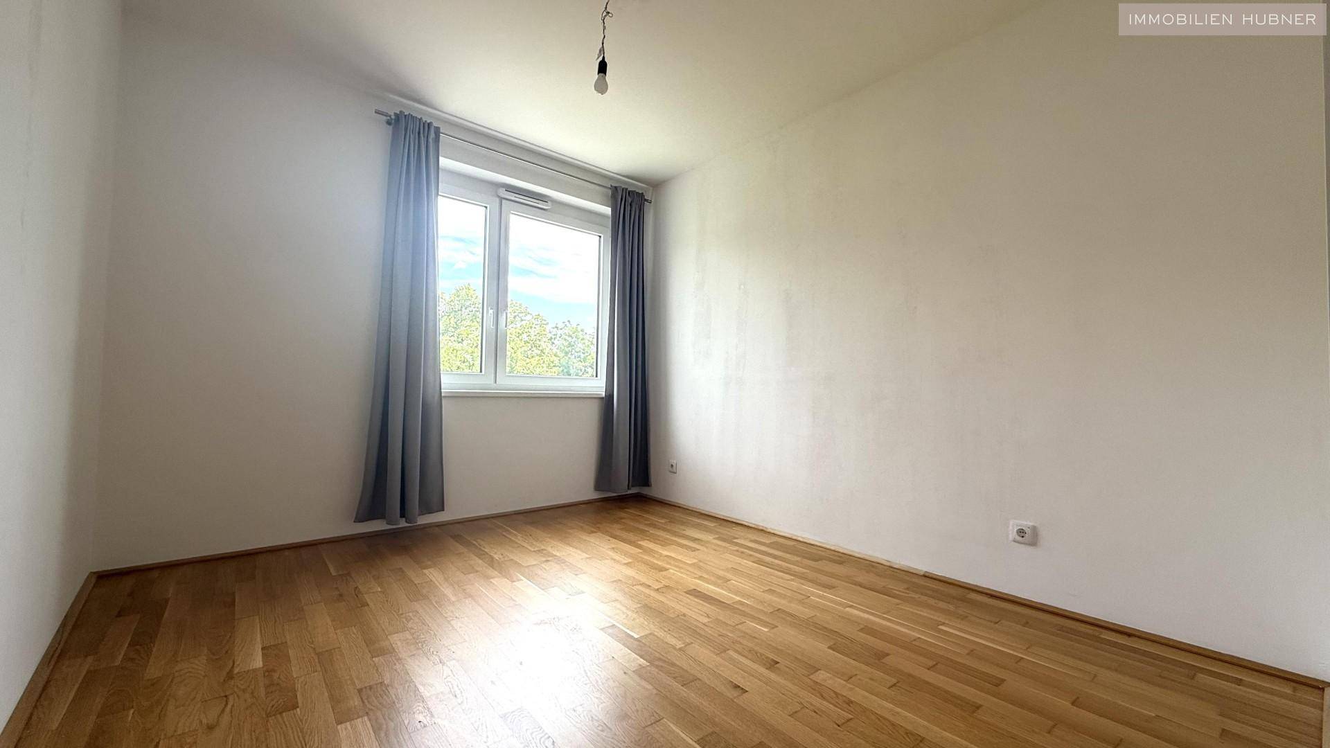 Geräumiges Zimmer mit Parkettboden und Fenster, ideal als Schlaf- oder Arbeitszimmer nutzbar.