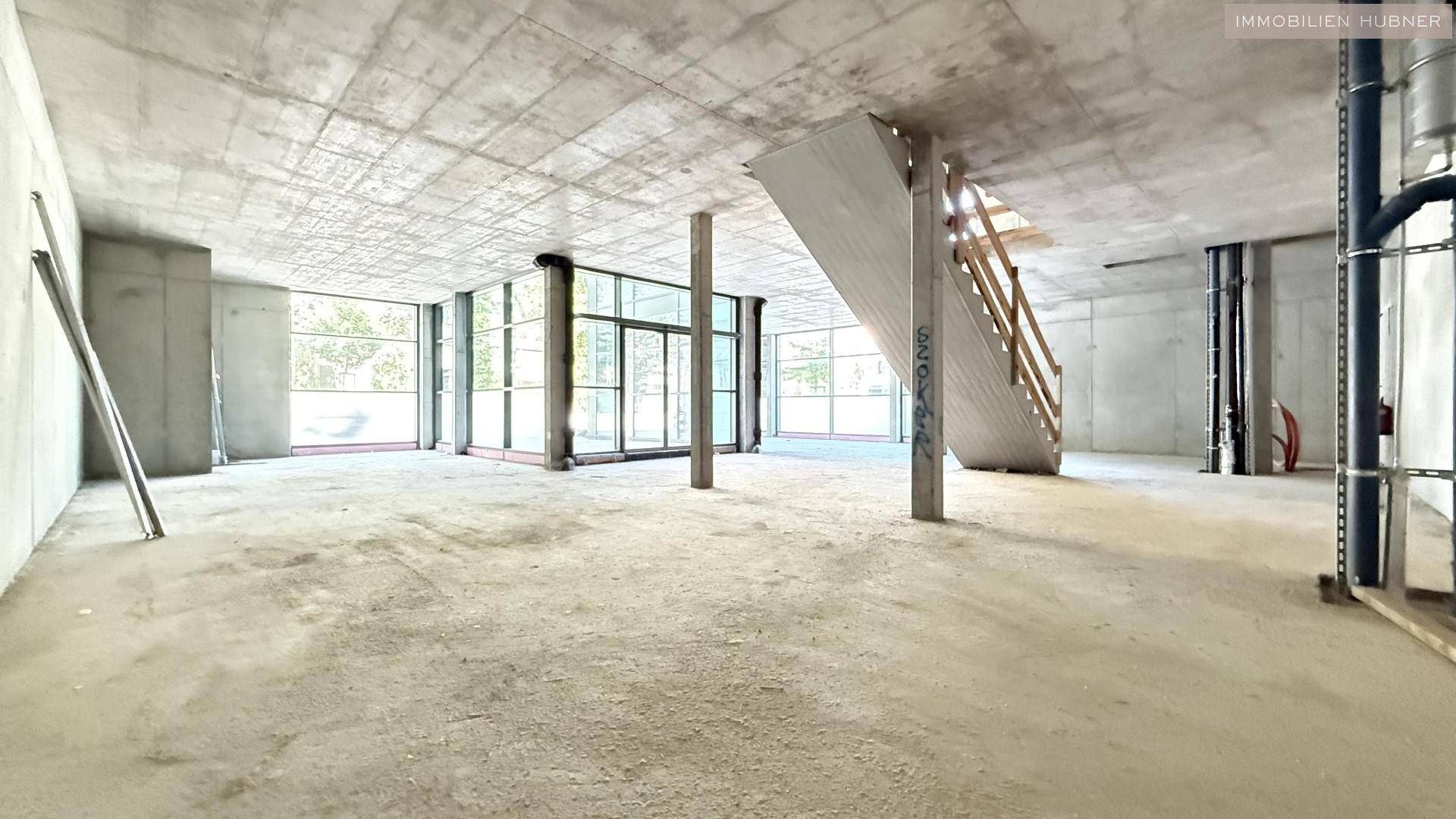 Großer, unfertiger Gewerberaum mit Betonboden und hohen Decken, bereit für den Ausbau.