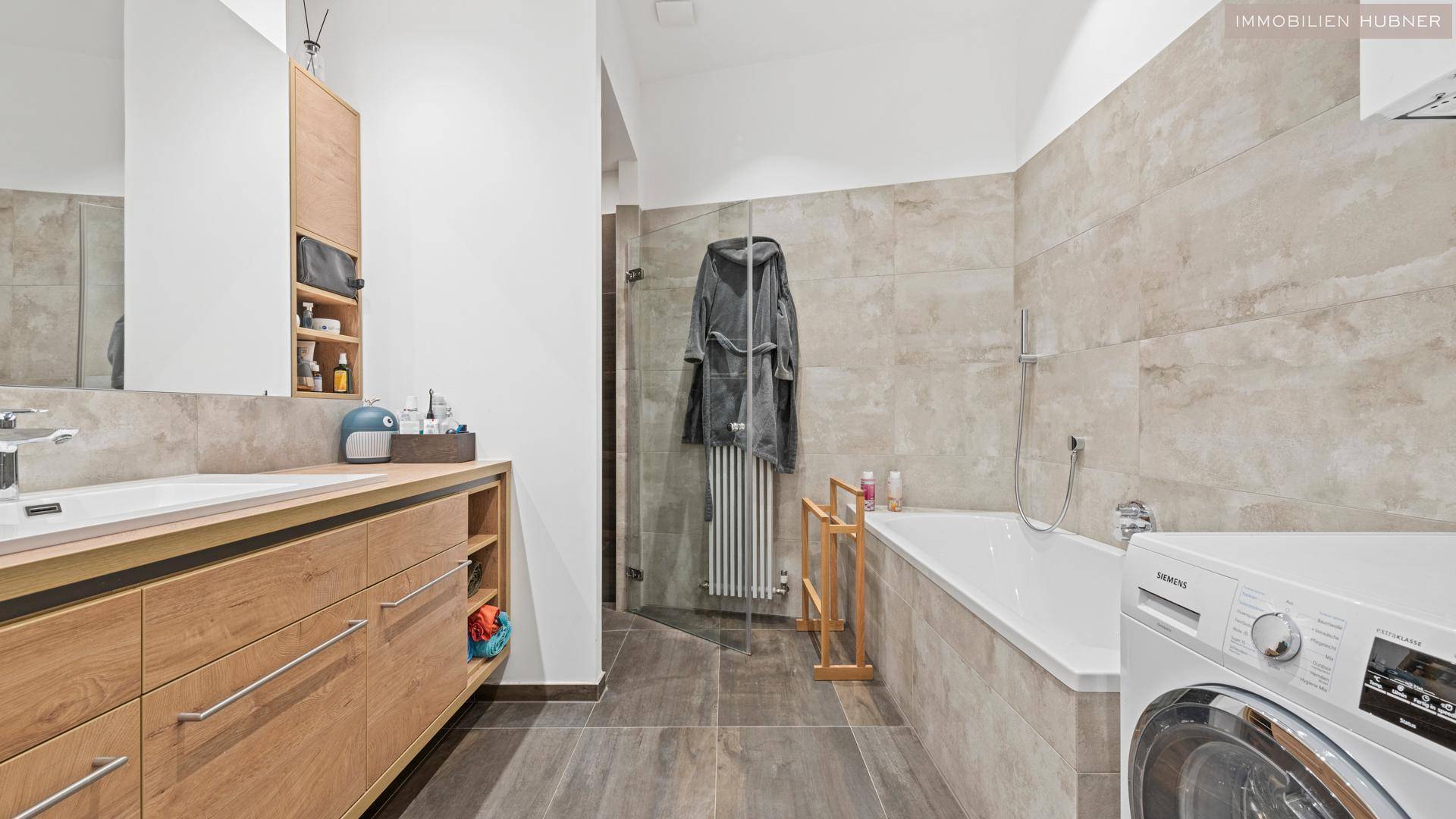 Modernes Badezimmer mit Waschtisch, Badewanne, Dusche und Waschmaschine.