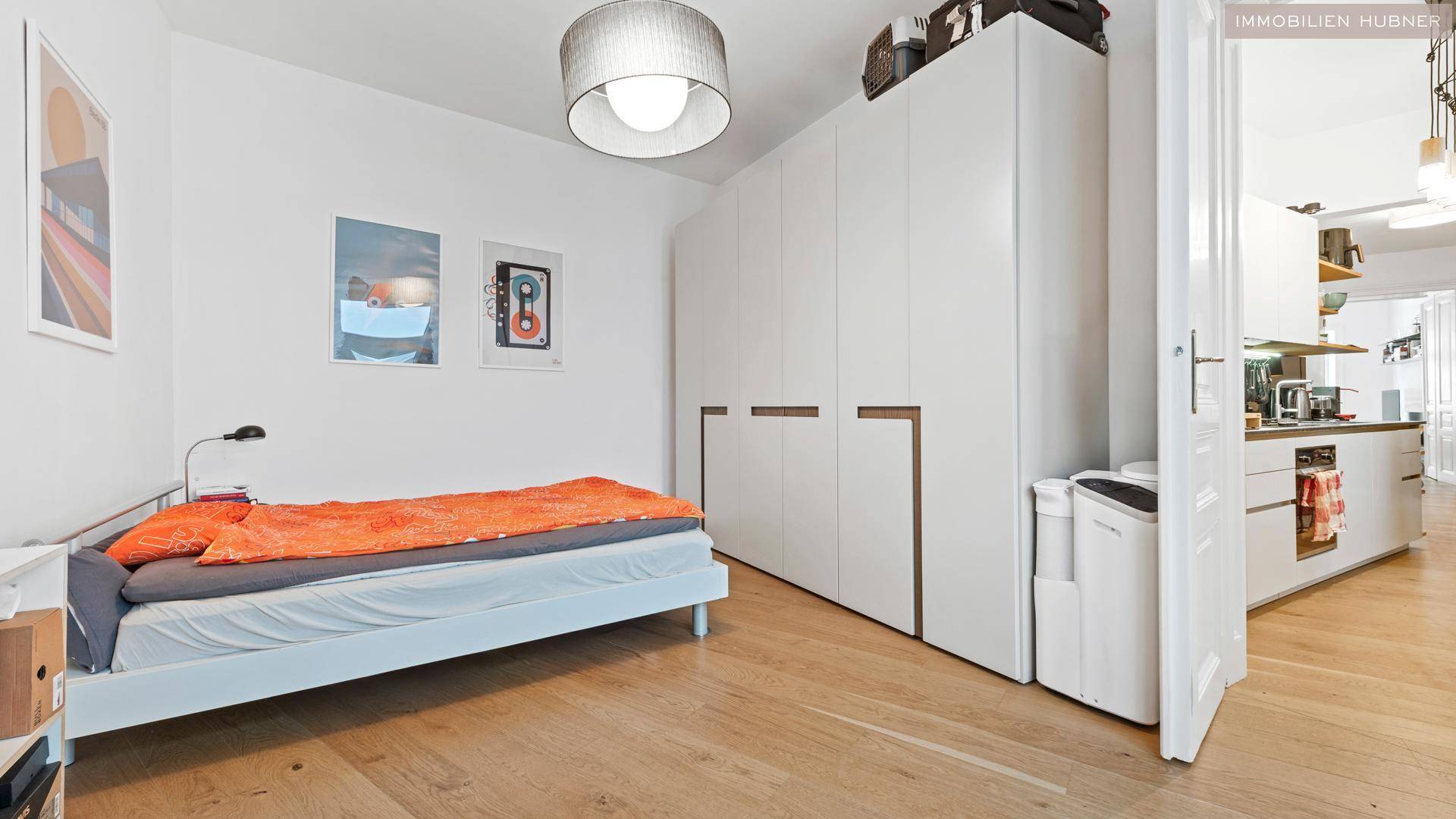 Helles Schlafzimmer mit Einzelbett, großem Kleiderschrank und Holzboden.