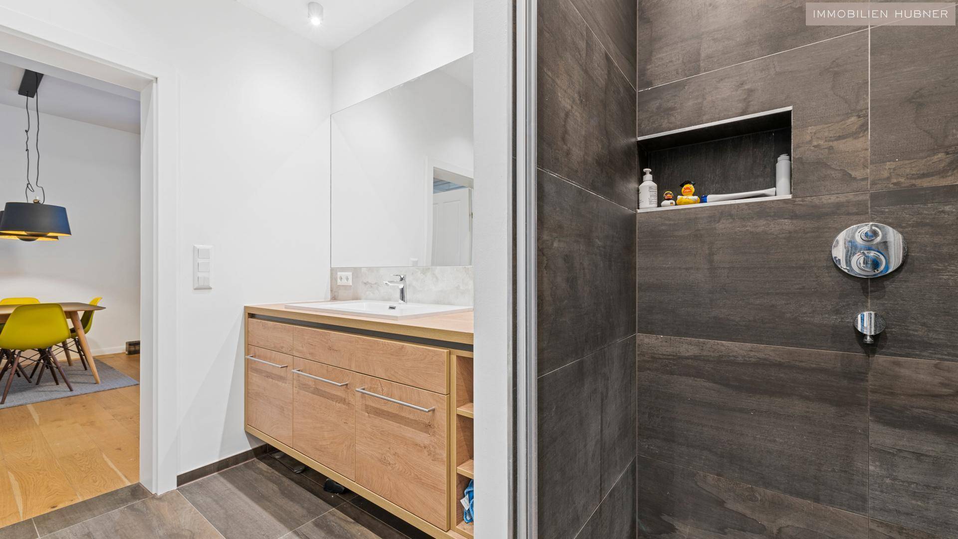 Modernes Badezimmer mit Waschtisch, Spiegel und begehbarer Dusche.
