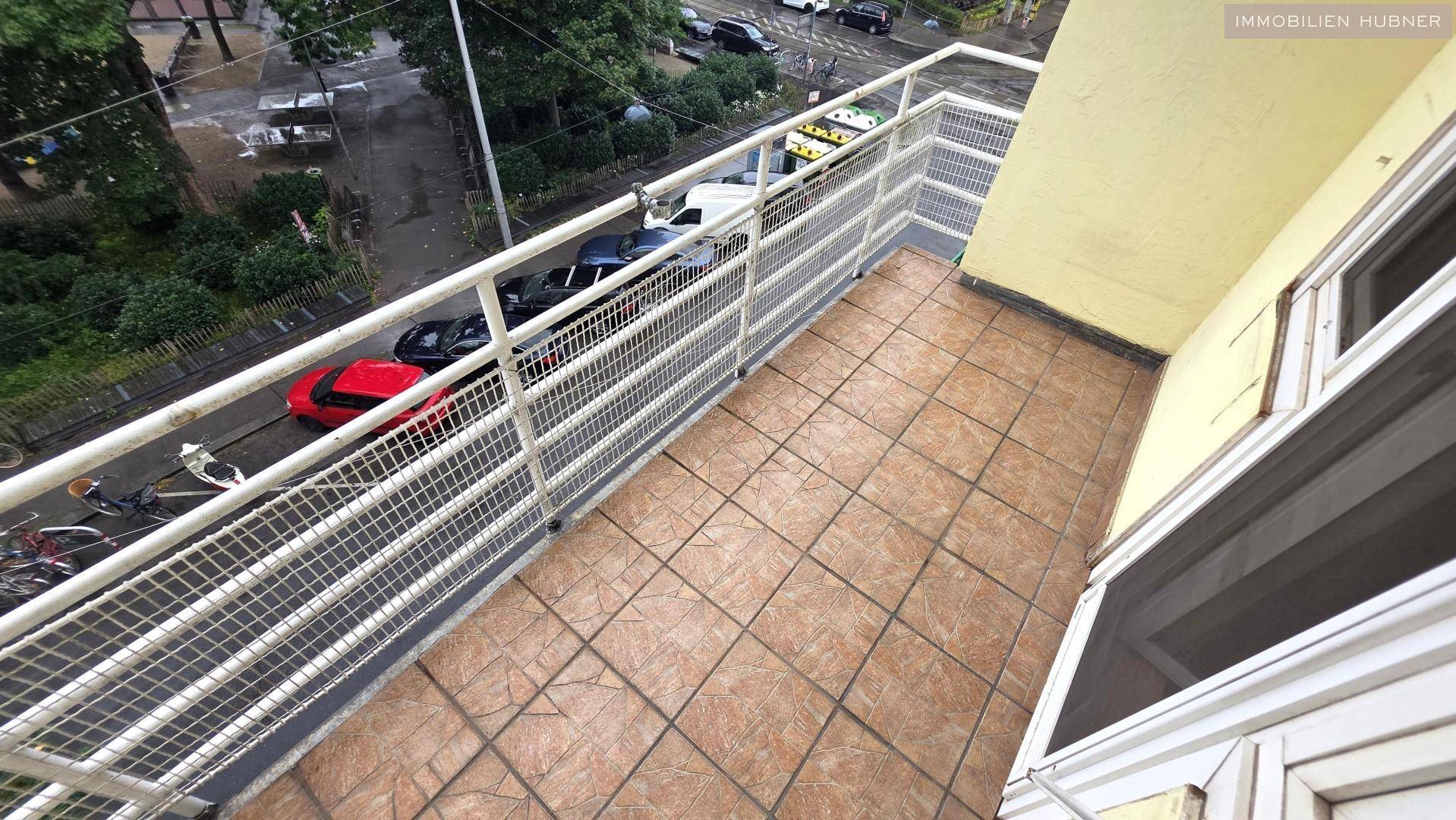 Kleiner Balkon mit Fliesenboden und Metallgeländer, bietet Blick auf die darunterliegende Straße.