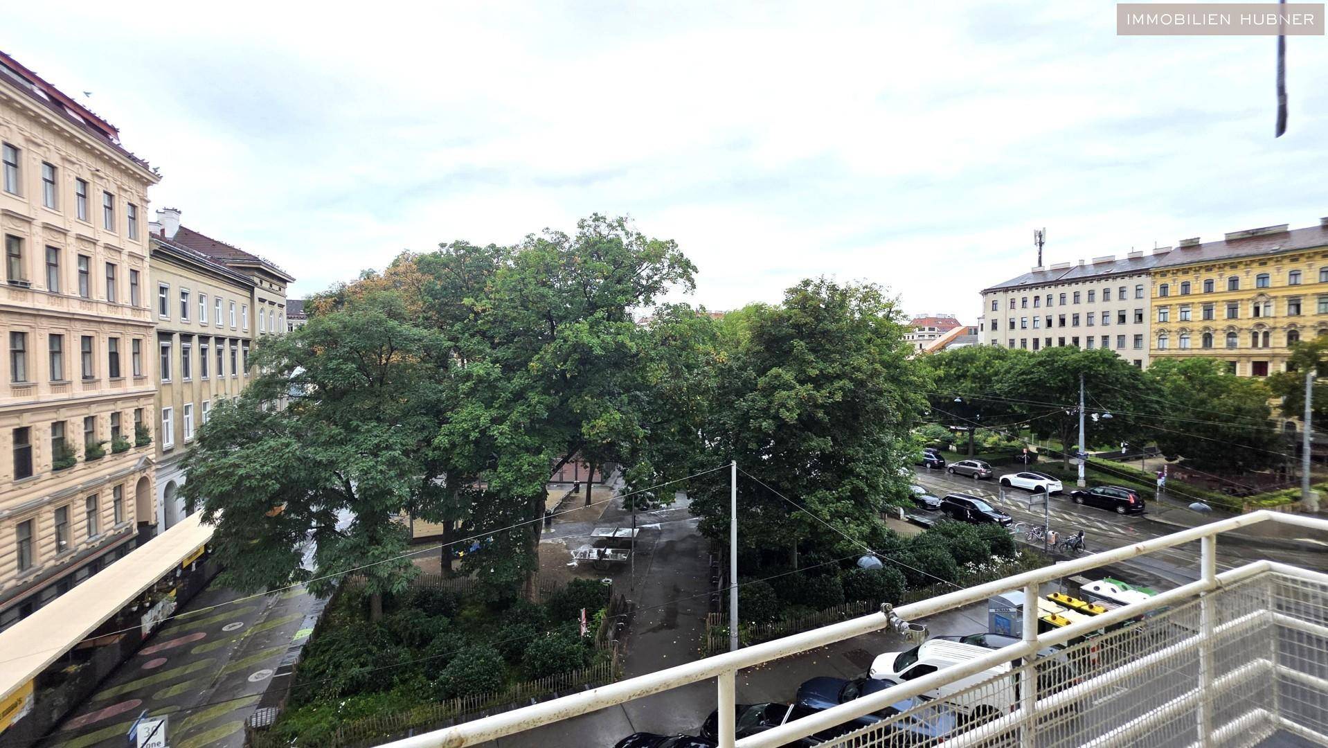 Weitläufiger Ausblick vom Balkon auf grüne Bäume und die umliegende Stadtbebauung.