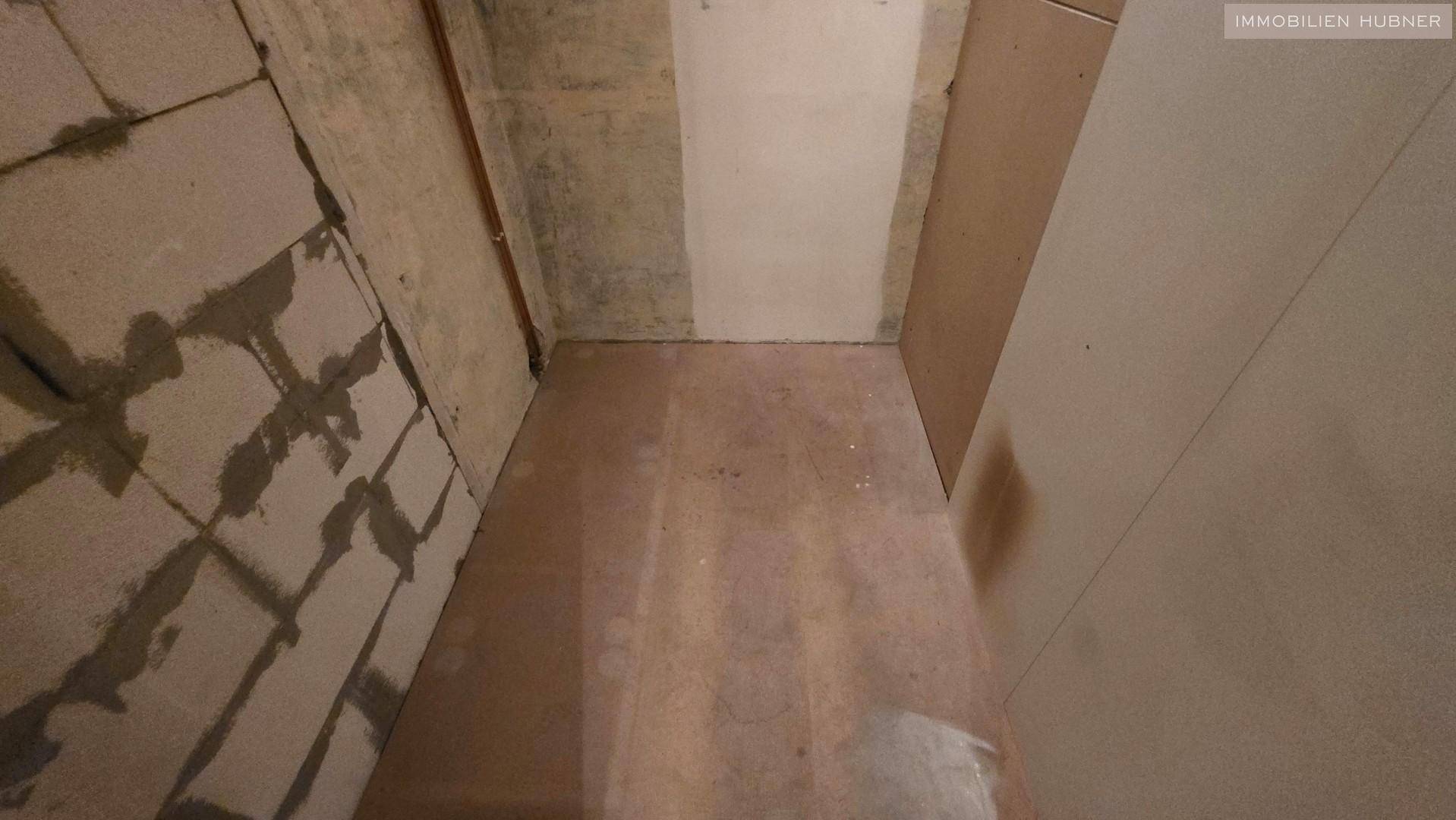 Unfertiger Raum mit rohen Wänden und Boden, bereit für den weiteren Ausbau der Immobilie.