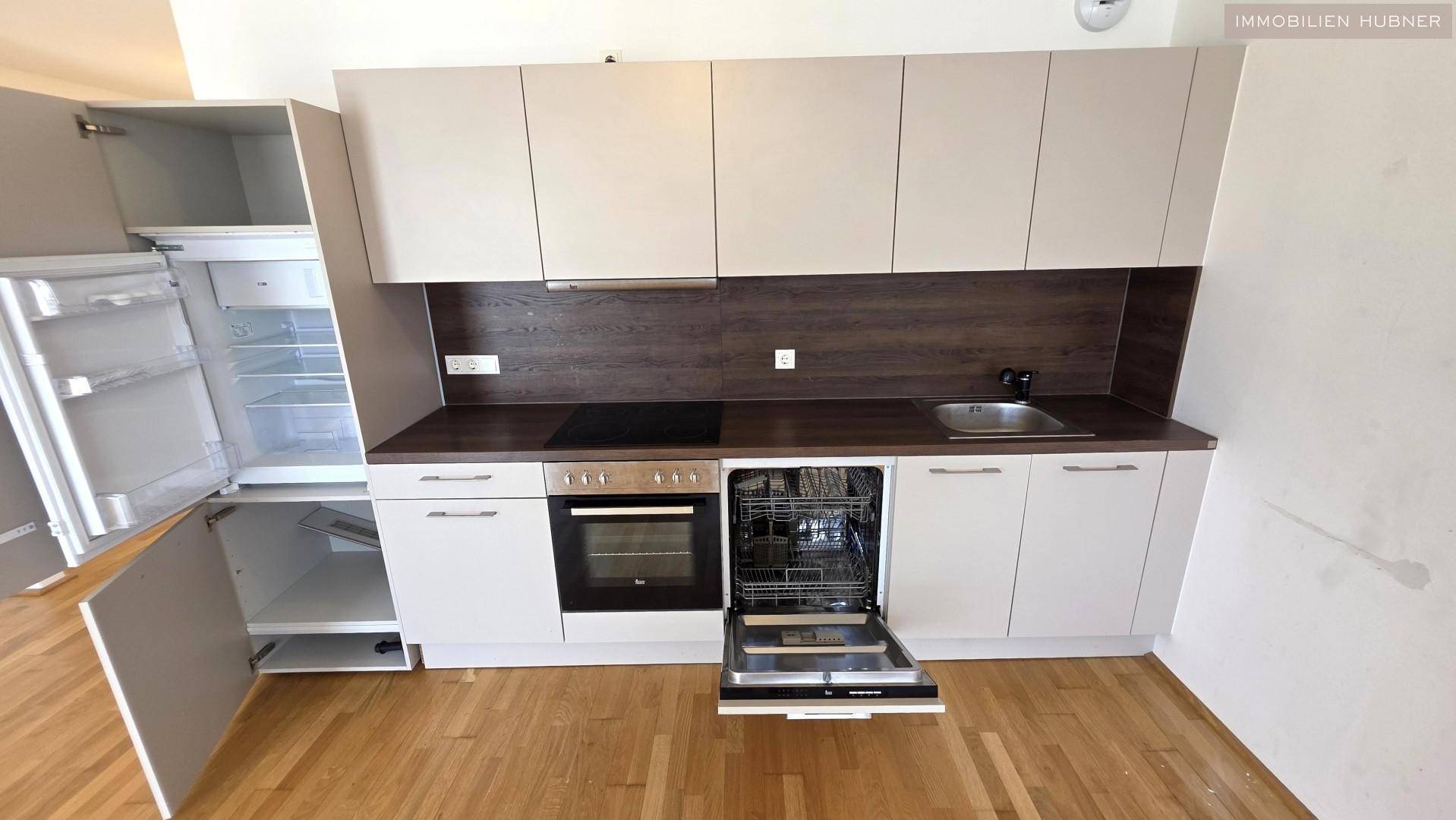 Moderne Küchenzeile mit integrierten Geräten wie Geschirrspüler, Backofen und Kühlschrank.