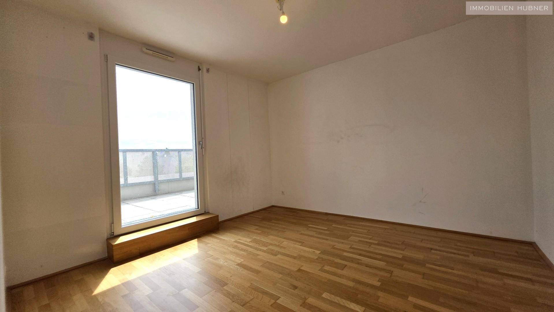 Helles Zimmer mit Parkettboden und direktem Zugang zur Terrasse, bietet viel Tageslicht.