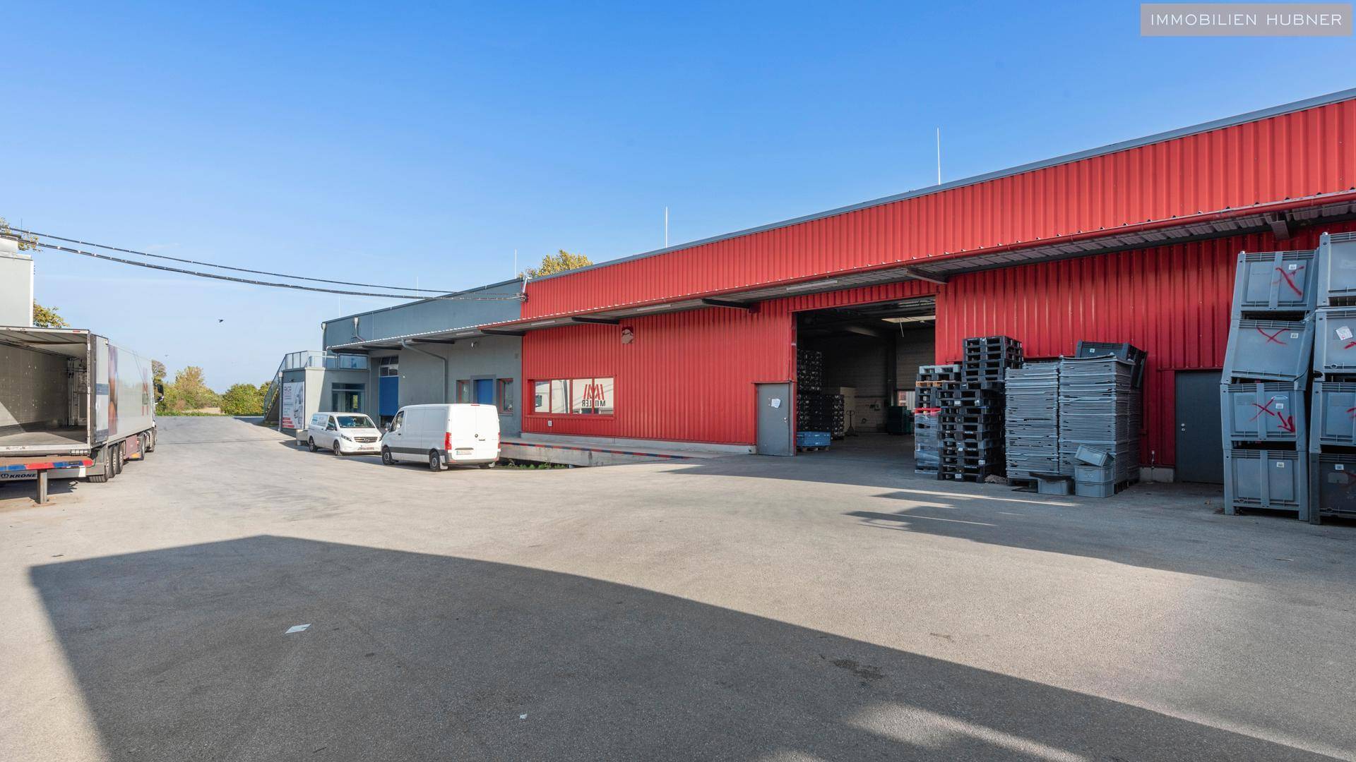 Außenansicht von Industriegebäuden mit Laderampen und parkenden Lieferwagen auf dem Gelände.