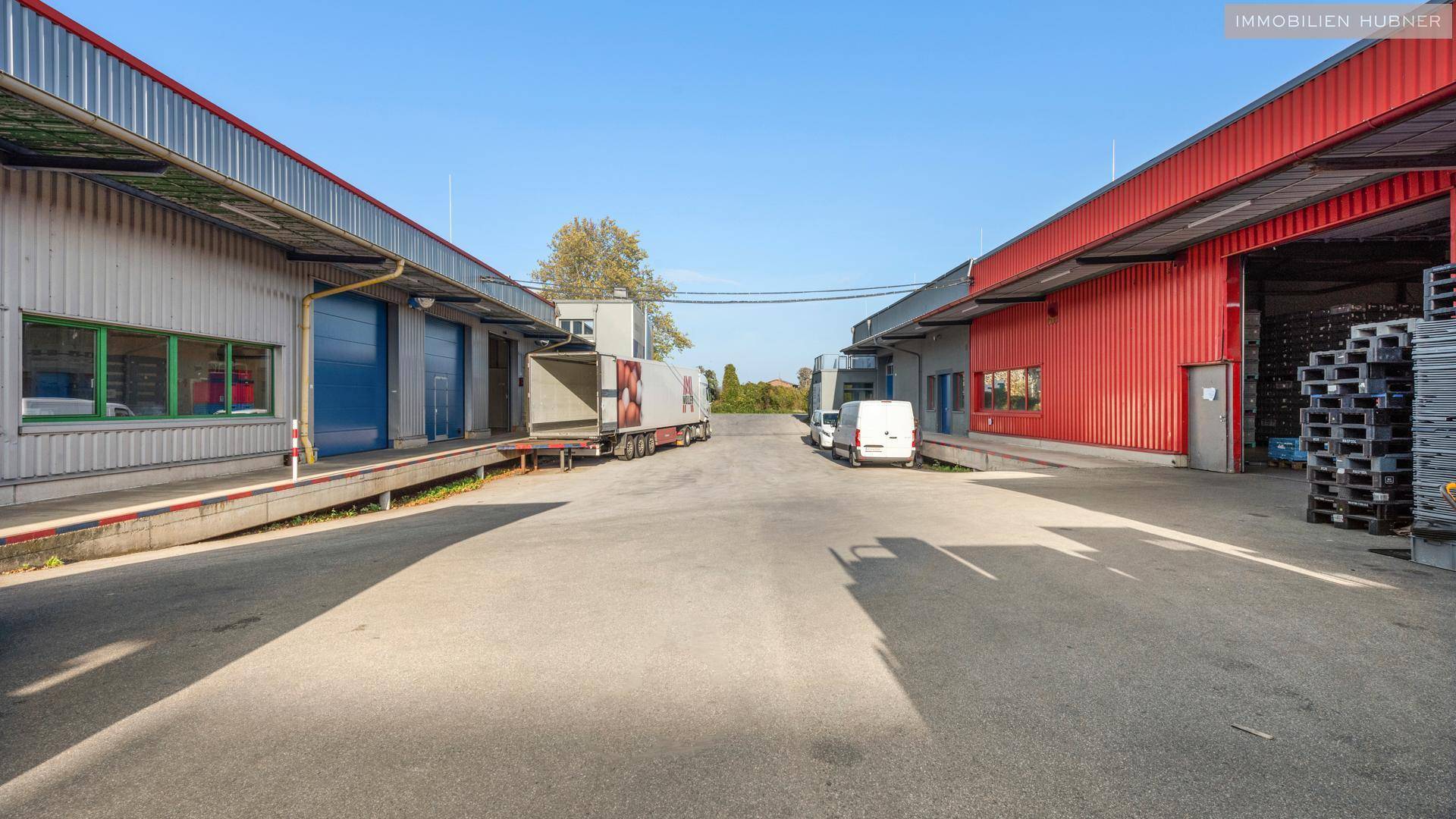 Zwischen zwei Industriegebäuden mit Laderampen und parkenden Lieferwagen auf dem Hof.