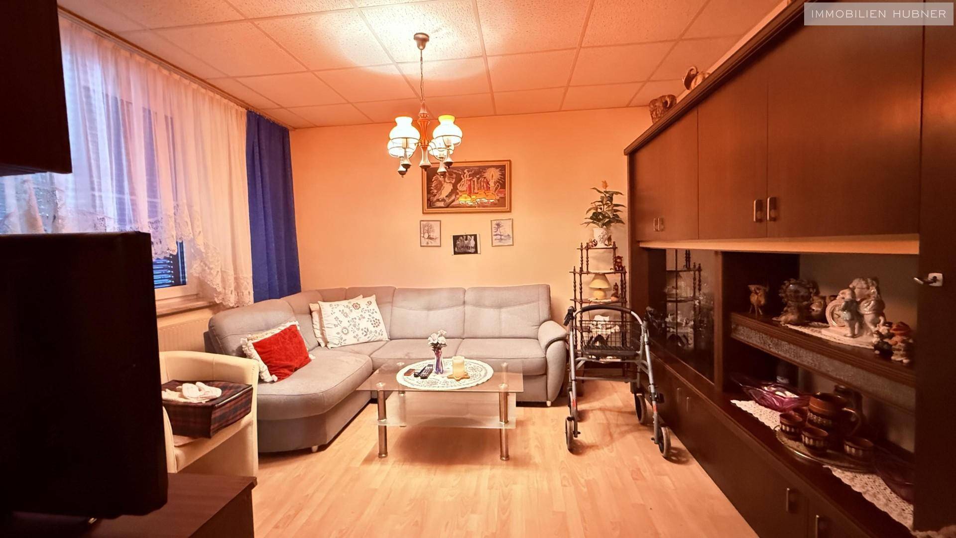 Gemütliches Wohnzimmer mit Ecksofa, Holzboden und traditionellen Möbeln.