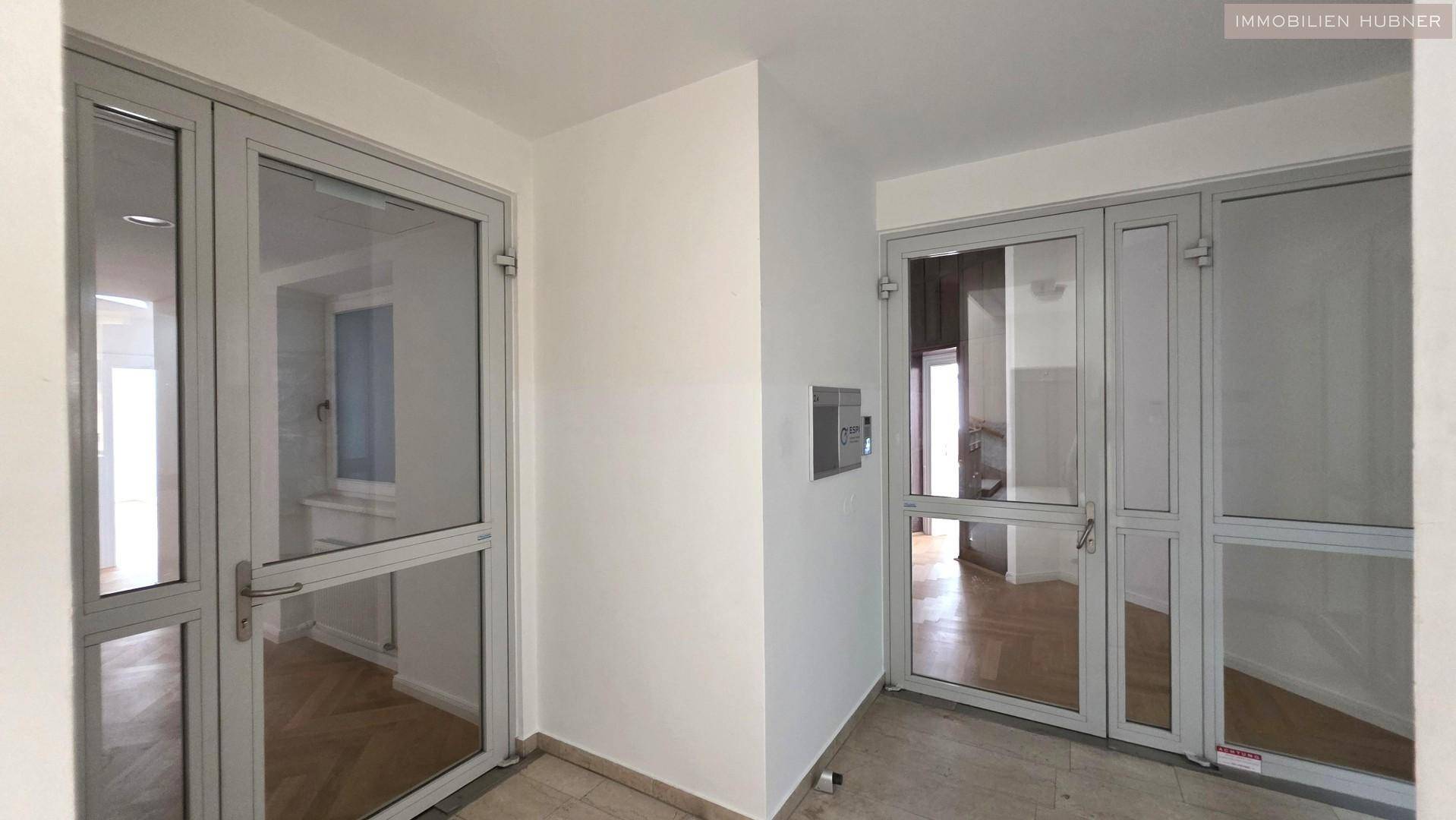 Heller Eingangsbereich mit modernen Glastüren, die Zugang zu den verschiedenen Räumen ermöglichen.