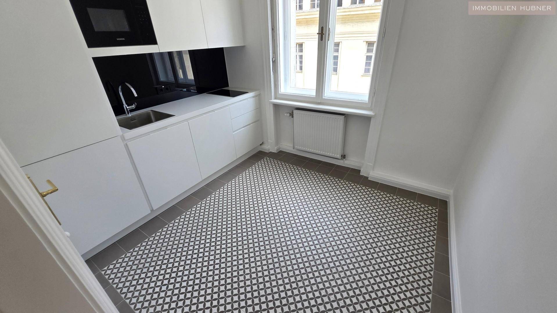 Kompakte, moderne Küche mit weißen Schränken, integrierten Geräten und einem Fenster mit Stadtblick.