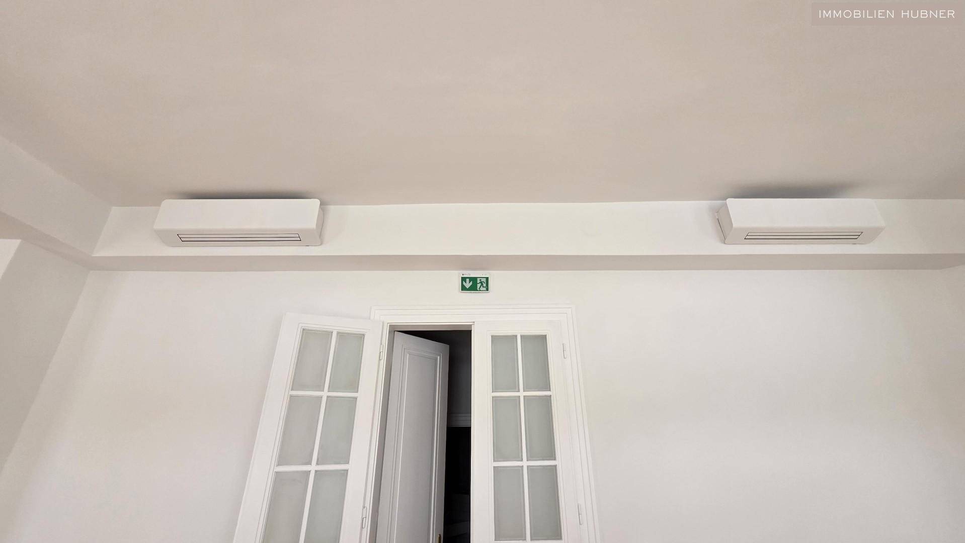 Detailaufnahme der Klimaanlagen an der Decke über einer Doppeltür in einem hellen Raum.