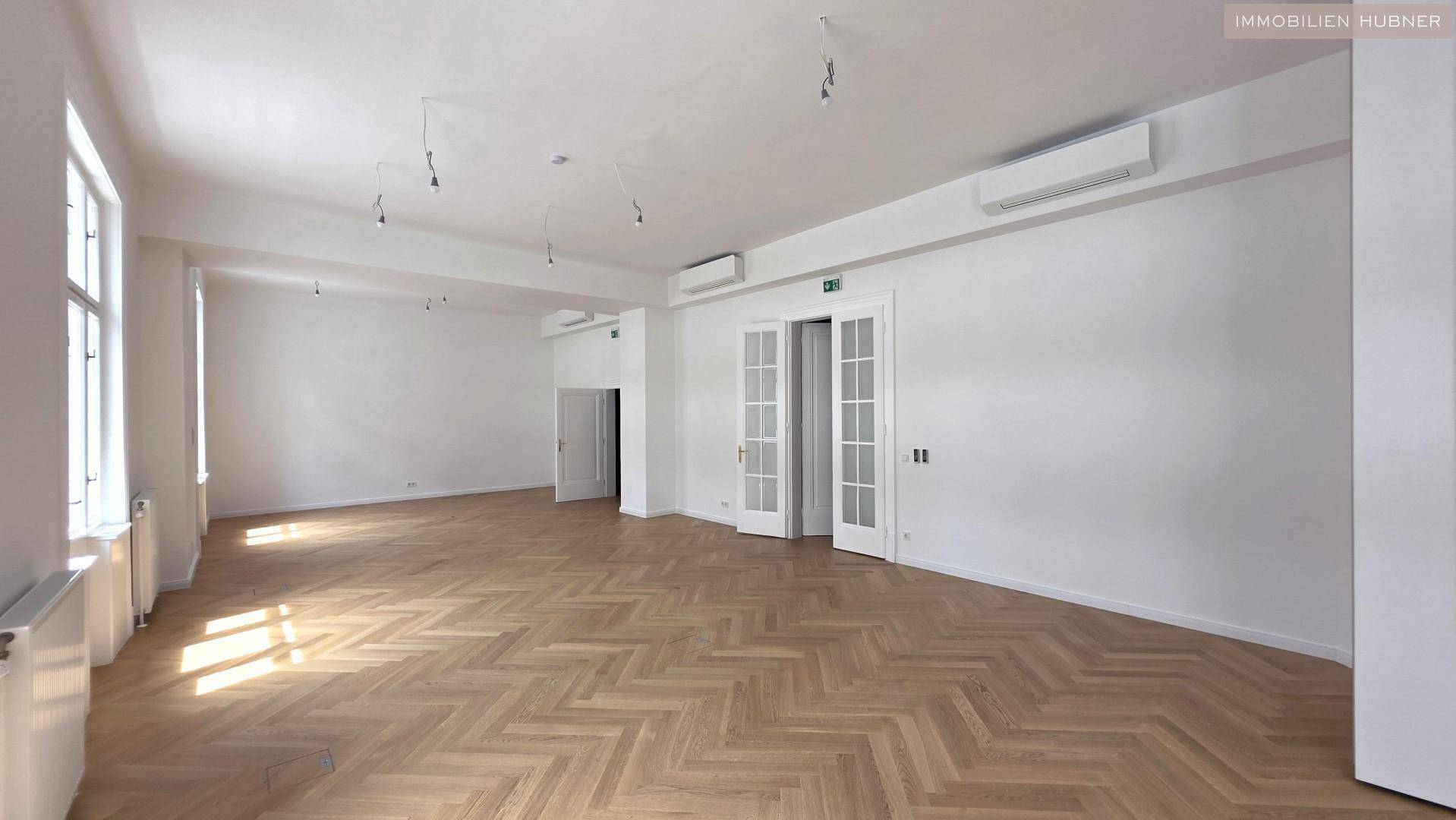 Geräumiger Bürobereich mit elegantem Fischgrätparkett und Klimaanlage, ideal für flexible Nutzung.